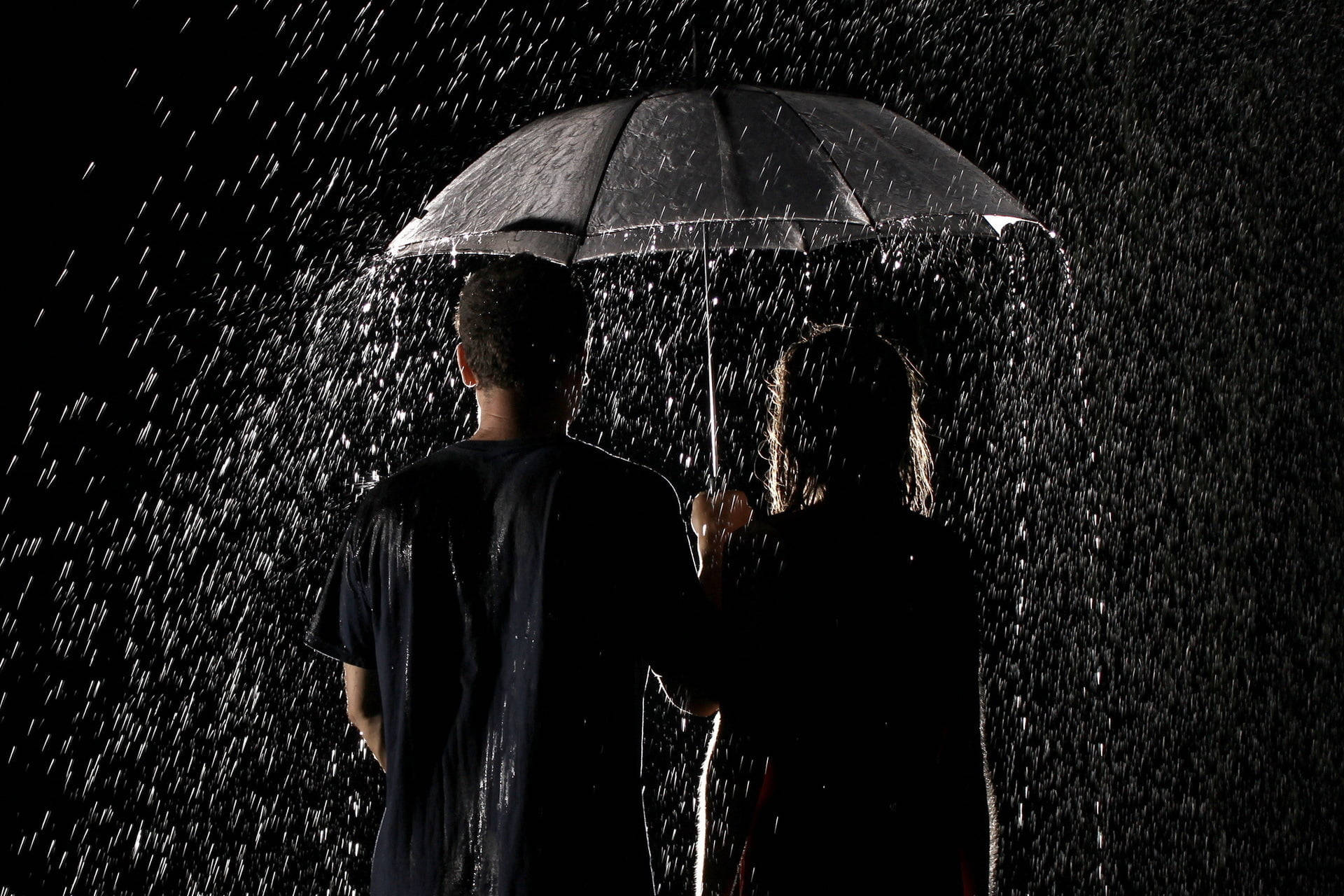 兩人在大雨的夜晚共用一把雨傘。