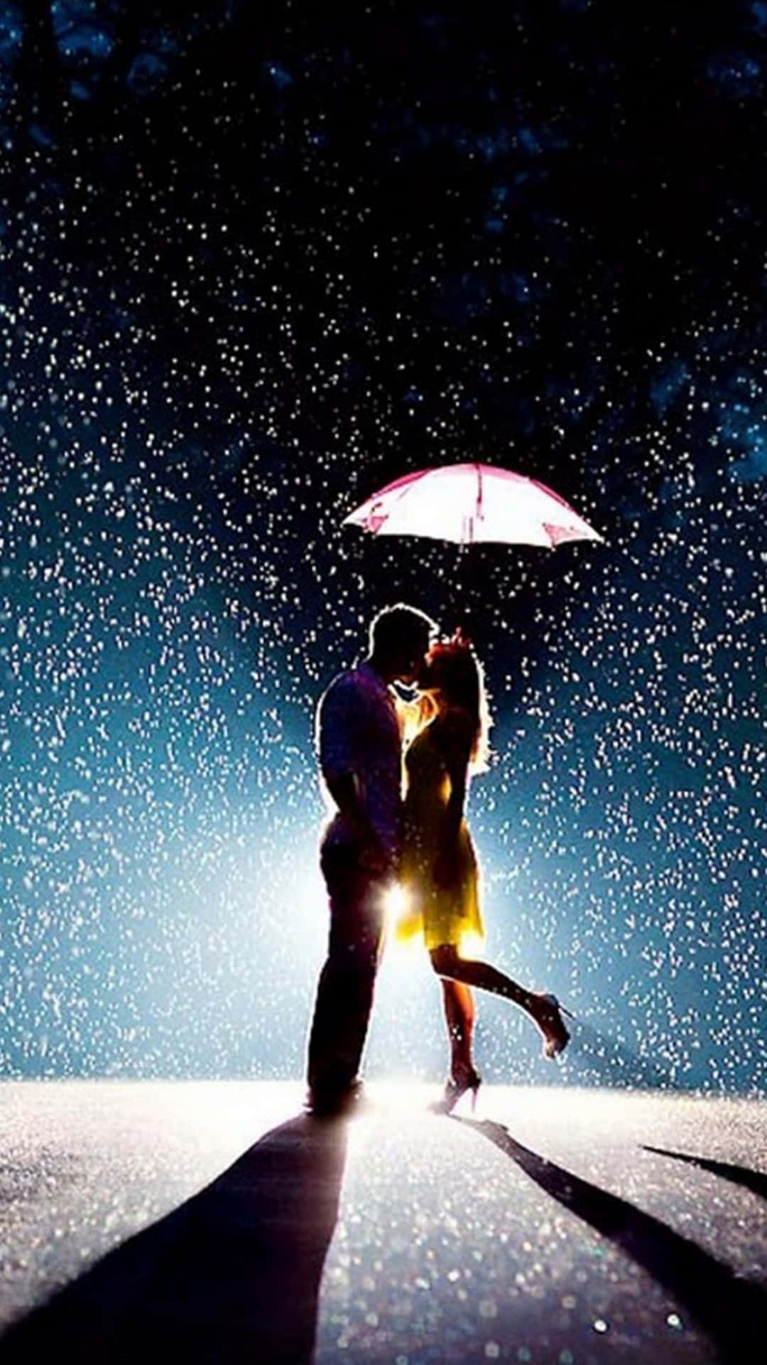 雨中擁吻浪漫背景 壁紙 — 一對剪影情侶在發光的粉紅色雨傘下接吻，雨水落在深藍色的夜空上。