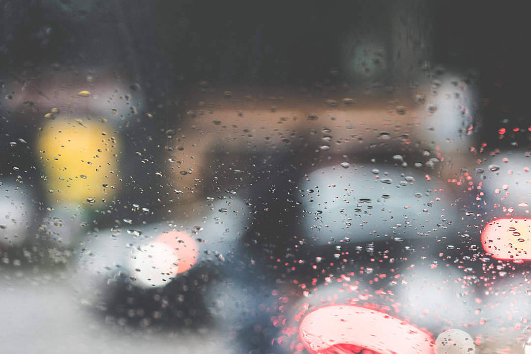 車窗上的雨滴，夜晚模糊的城市燈光。