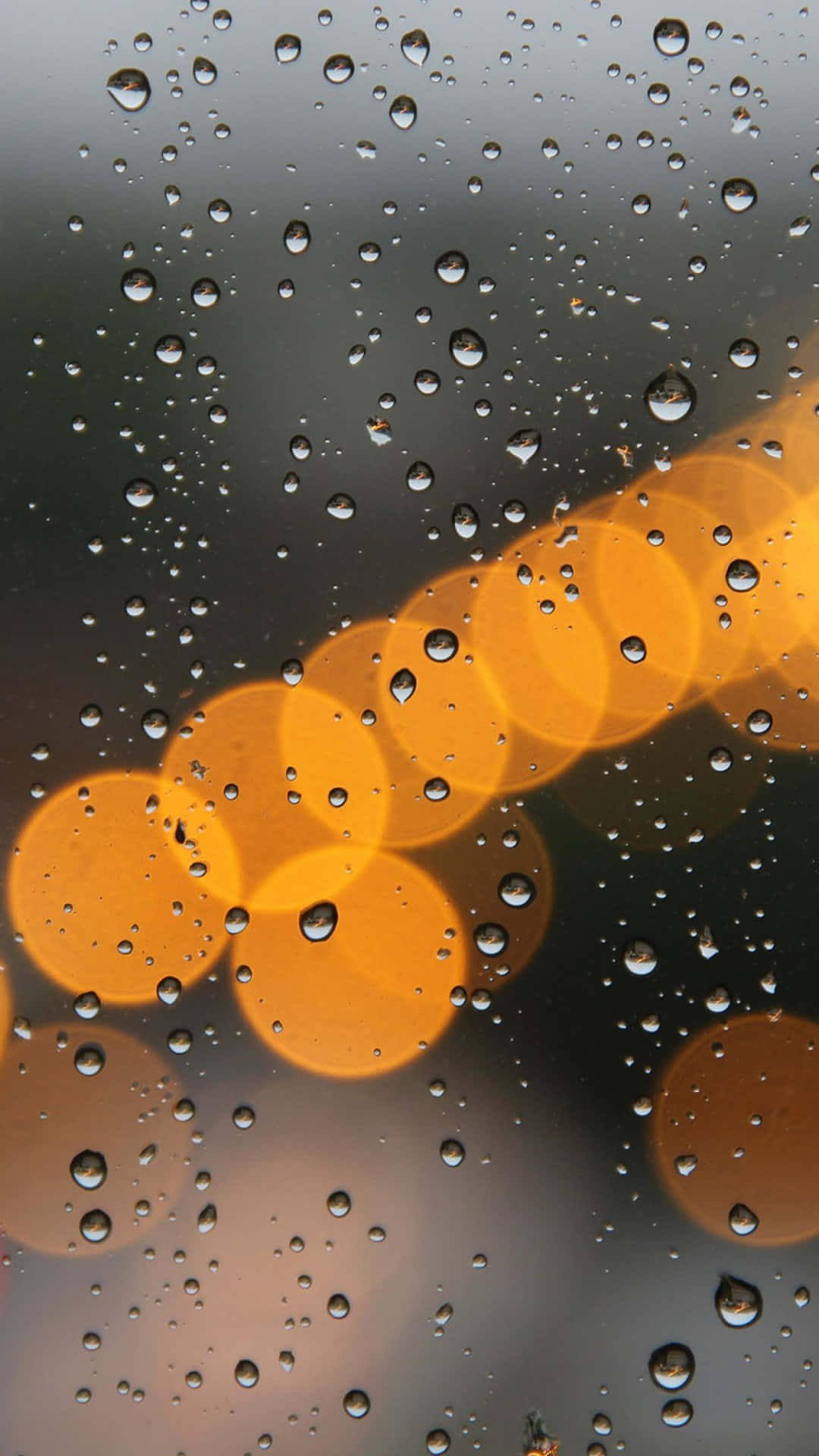 玻璃上的雨滴，背景是模糊的橙色街燈