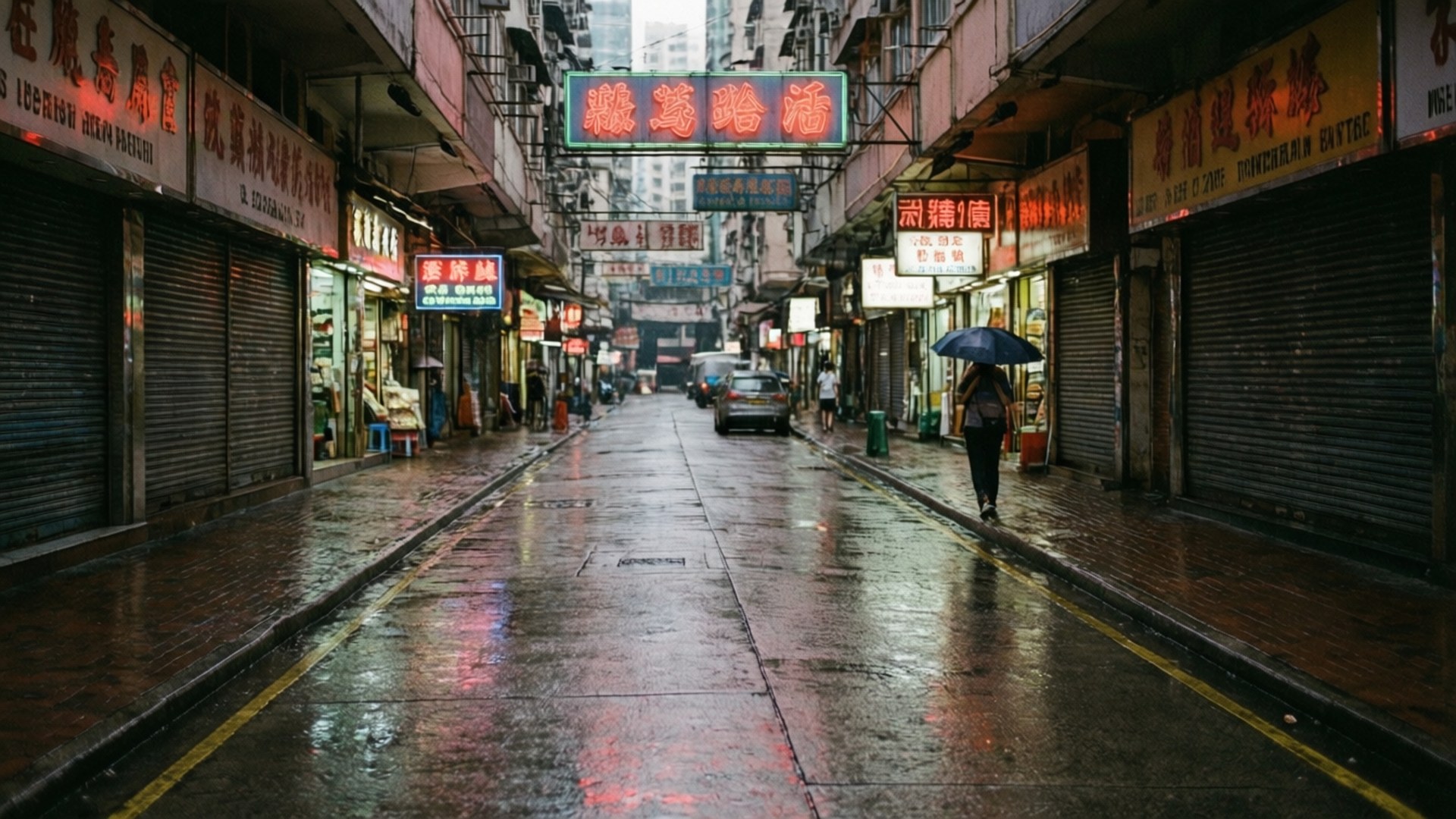雨中的旺角街頭 壁紙 — 一個孤獨的身影撐著傘，在雨夜的亞洲城市中走過一條狹窄潮濕的小巷，霓虹燈招牌倒映在路面上。