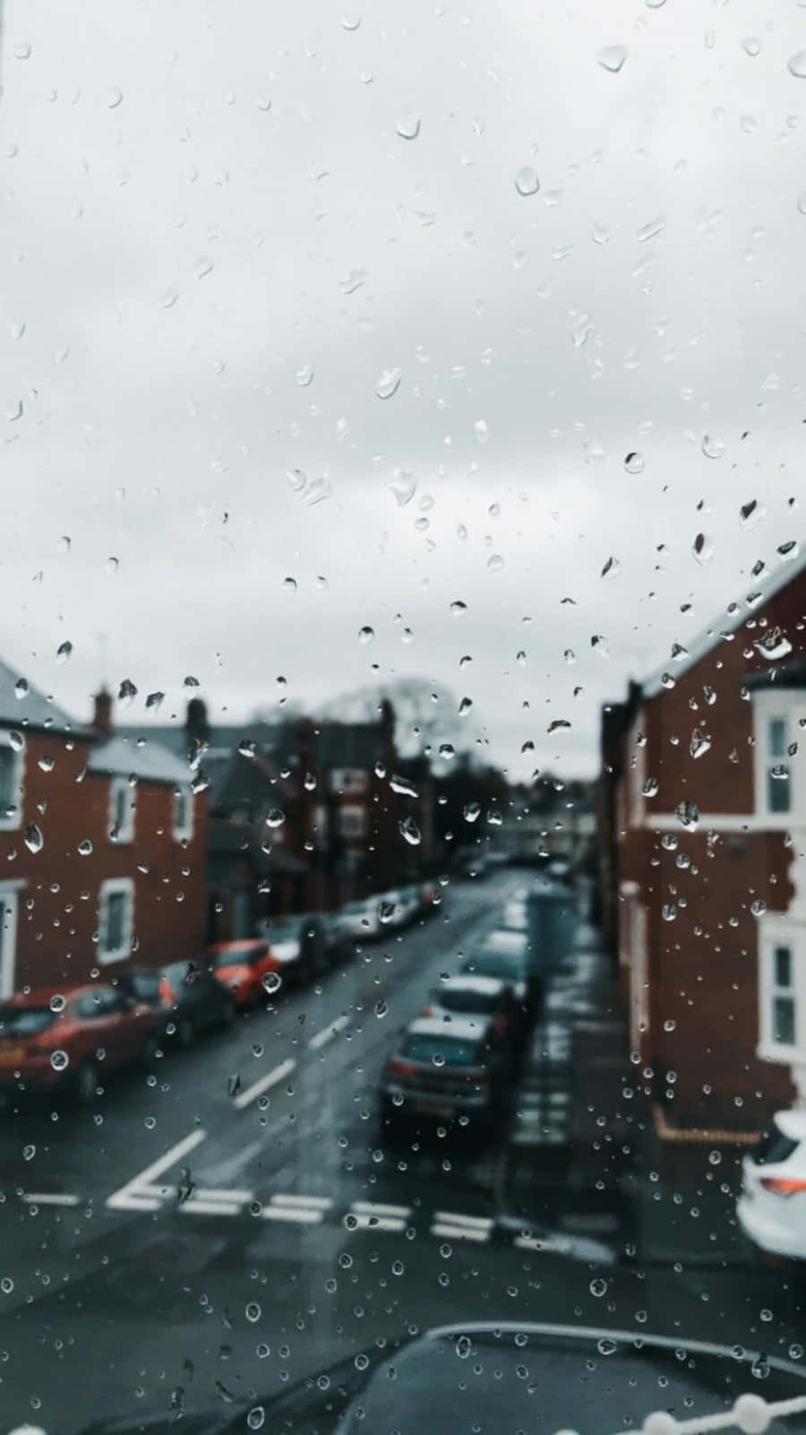 車窗上的雨滴，濕漉漉的街道和磚建築的景色。