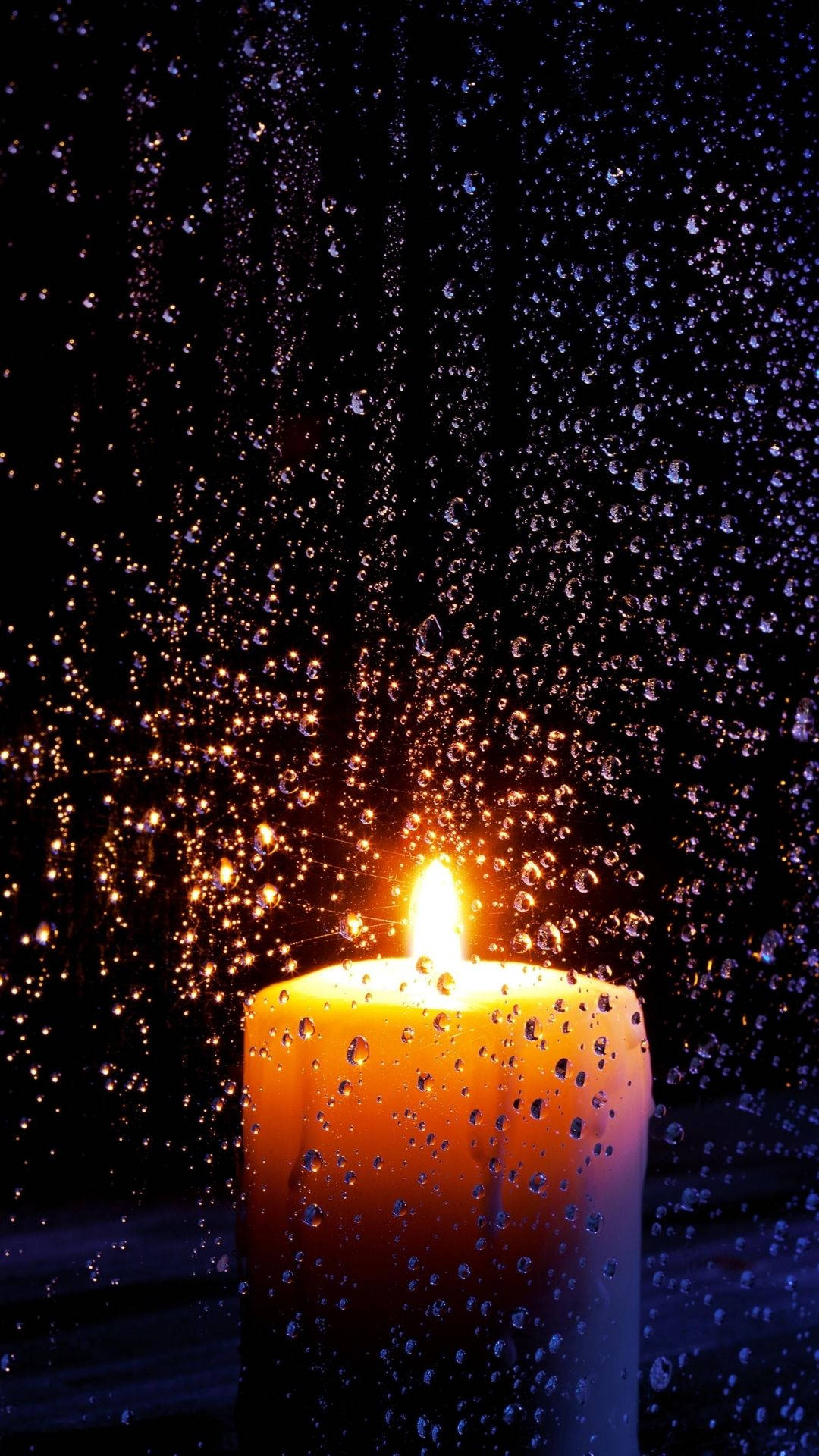 夜晚，蠟燭透過玻璃上的雨滴明亮地燃燒。 — 蠟燭 GIF 壁紙