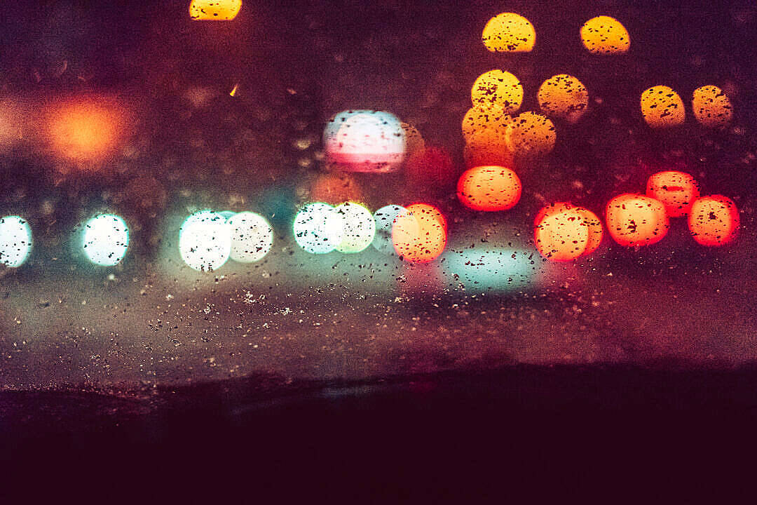 車窗上的雨滴將城市燈光模糊成色彩繽紛的球體，在夜間。