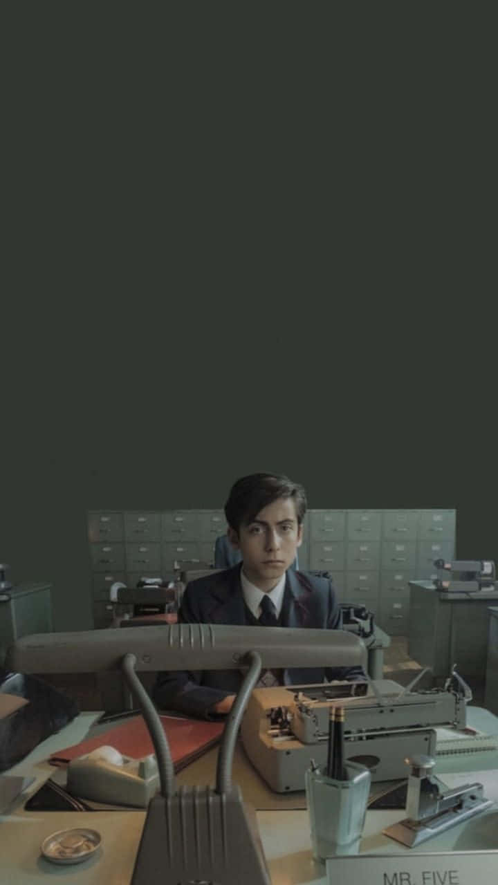 一位身穿西裝的年輕男子坐在一台復古打字機前，身處一個昏暗的辦公室，周圍有文件櫃。