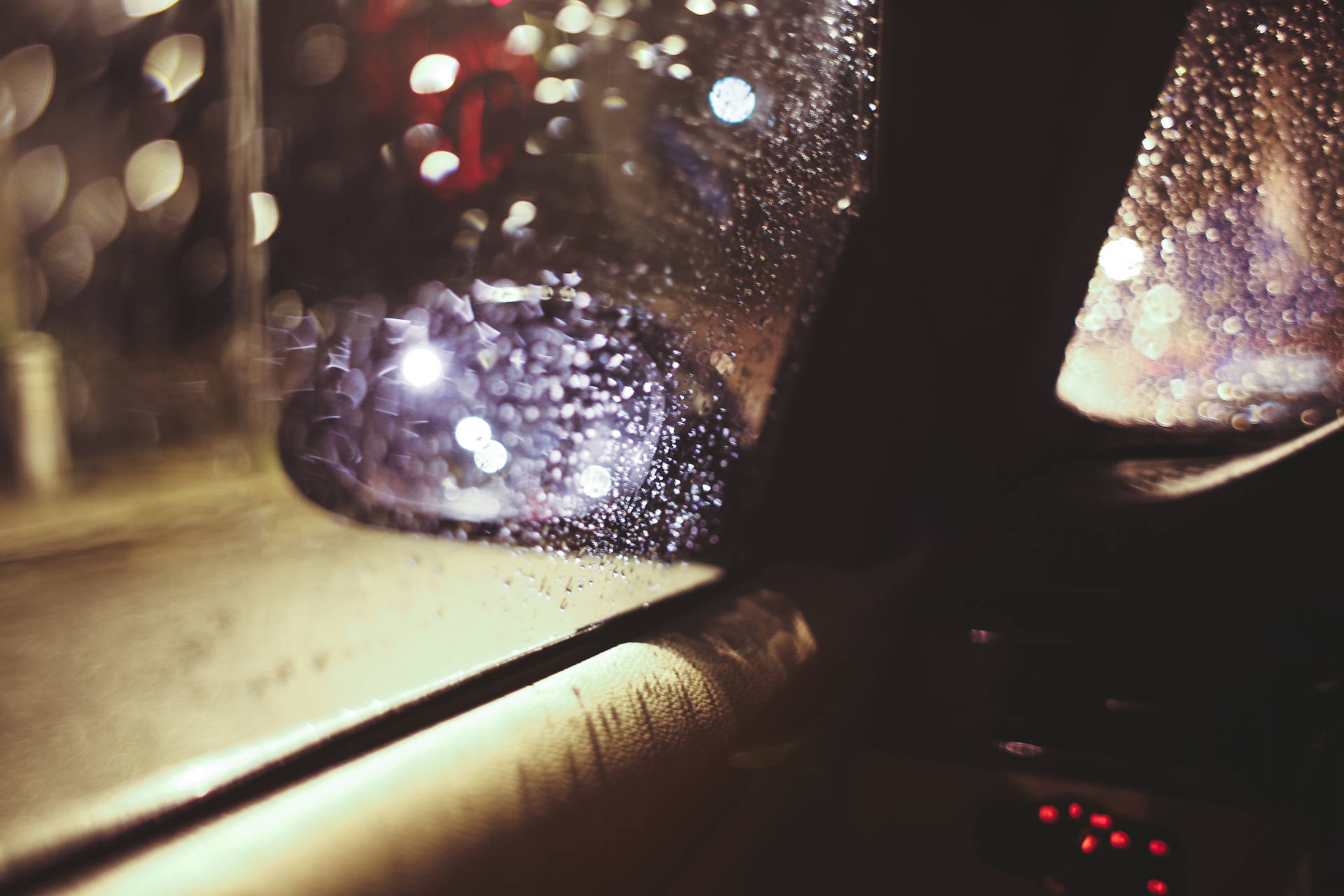 夜晚車窗上的雨滴，模糊的城市燈光透射進來。
