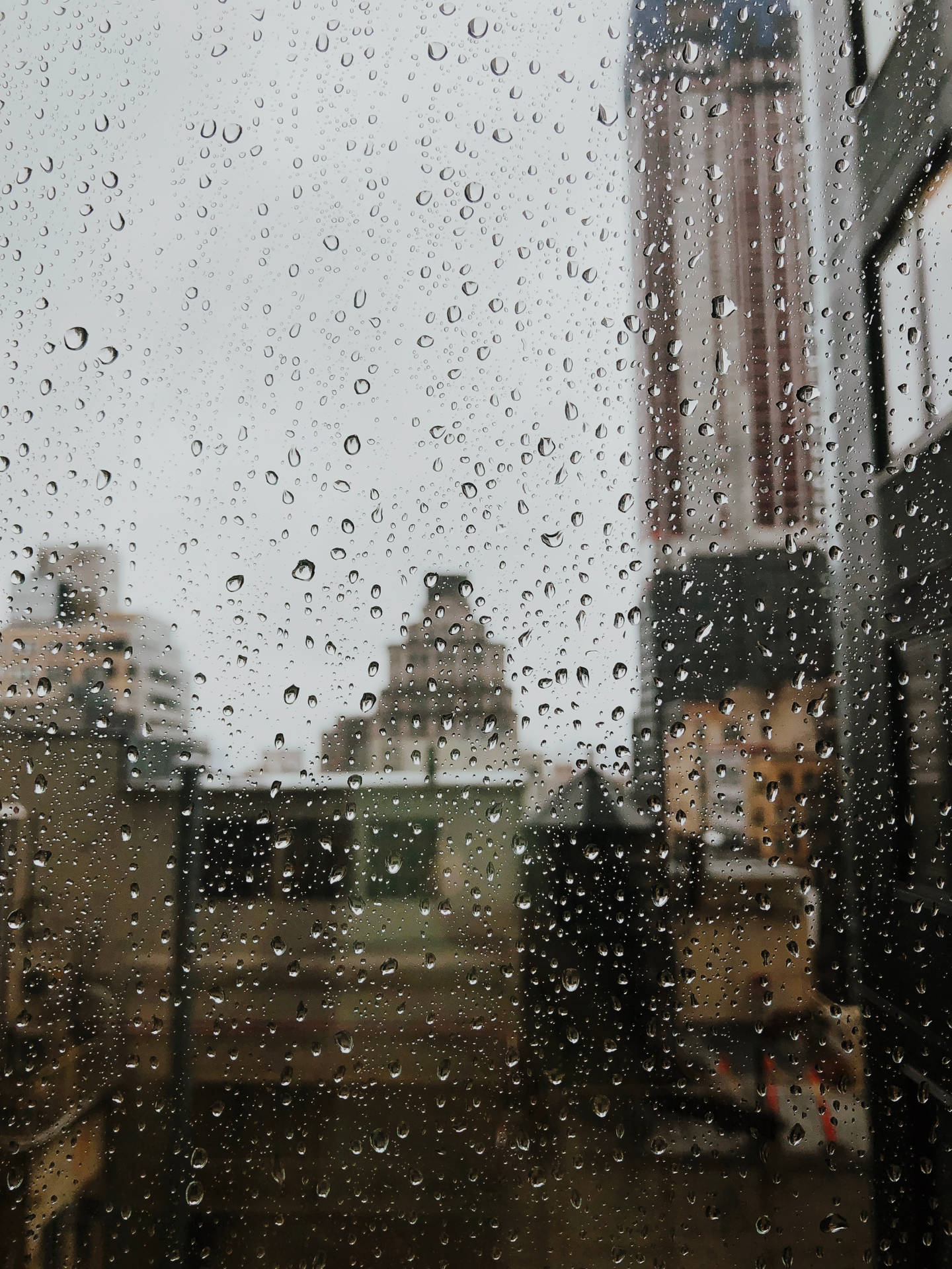 窗戶上的雨滴，背後是模糊的城市景色。
