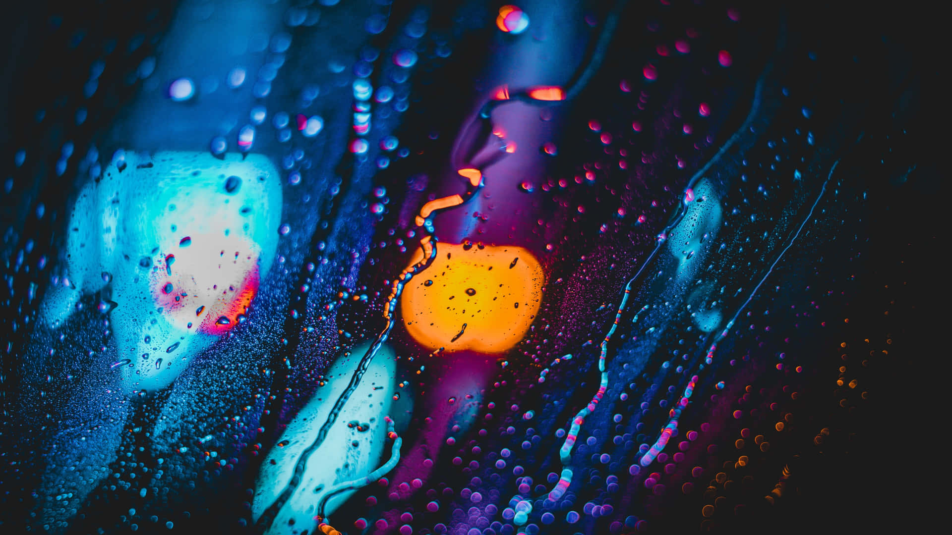 玻璃上的雨滴反射出霓虹燈光，形成色彩繽紛的抽象圖案。