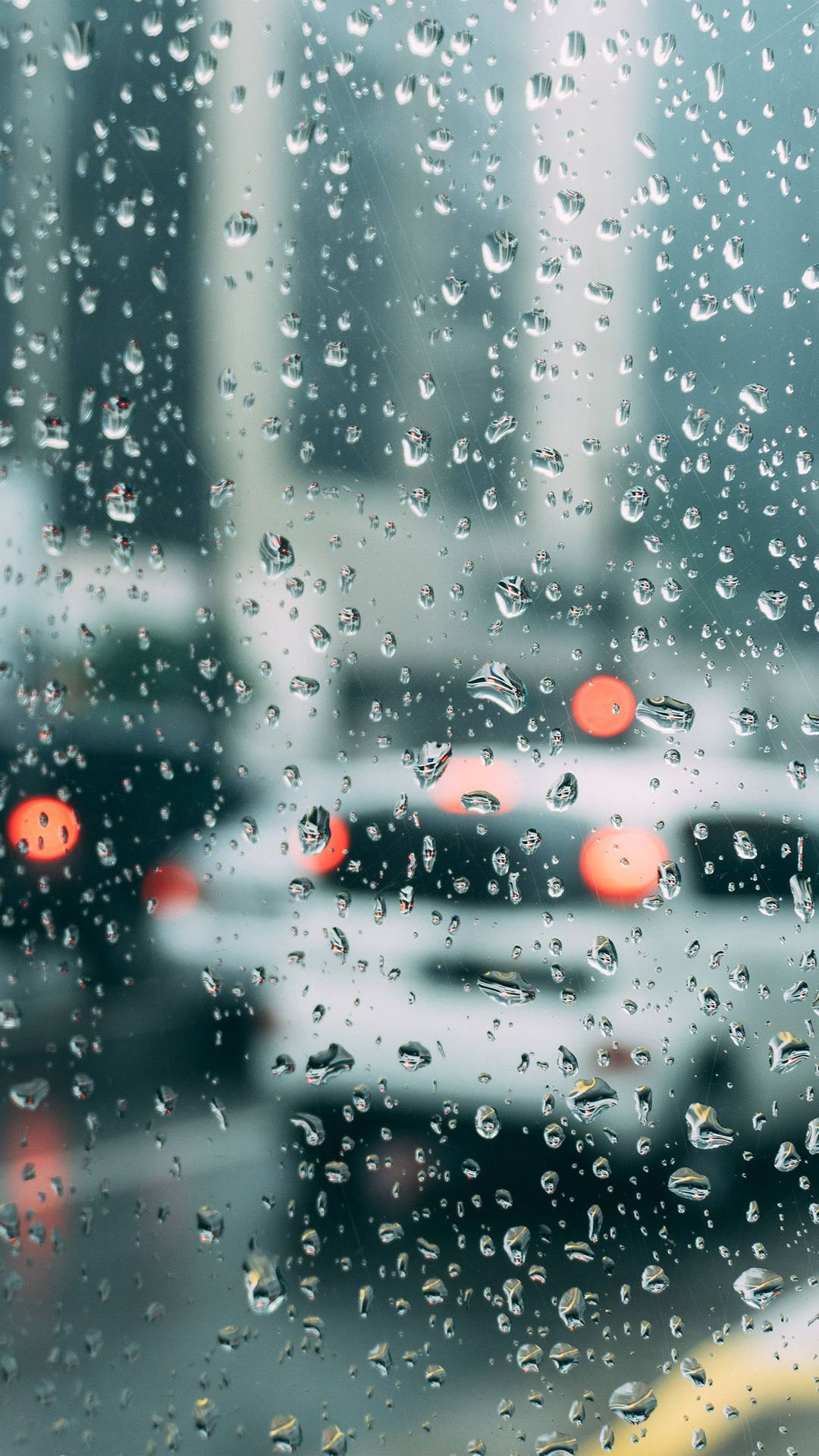 窗戶上的雨滴，模糊的城市燈光和夜晚經過的汽車。