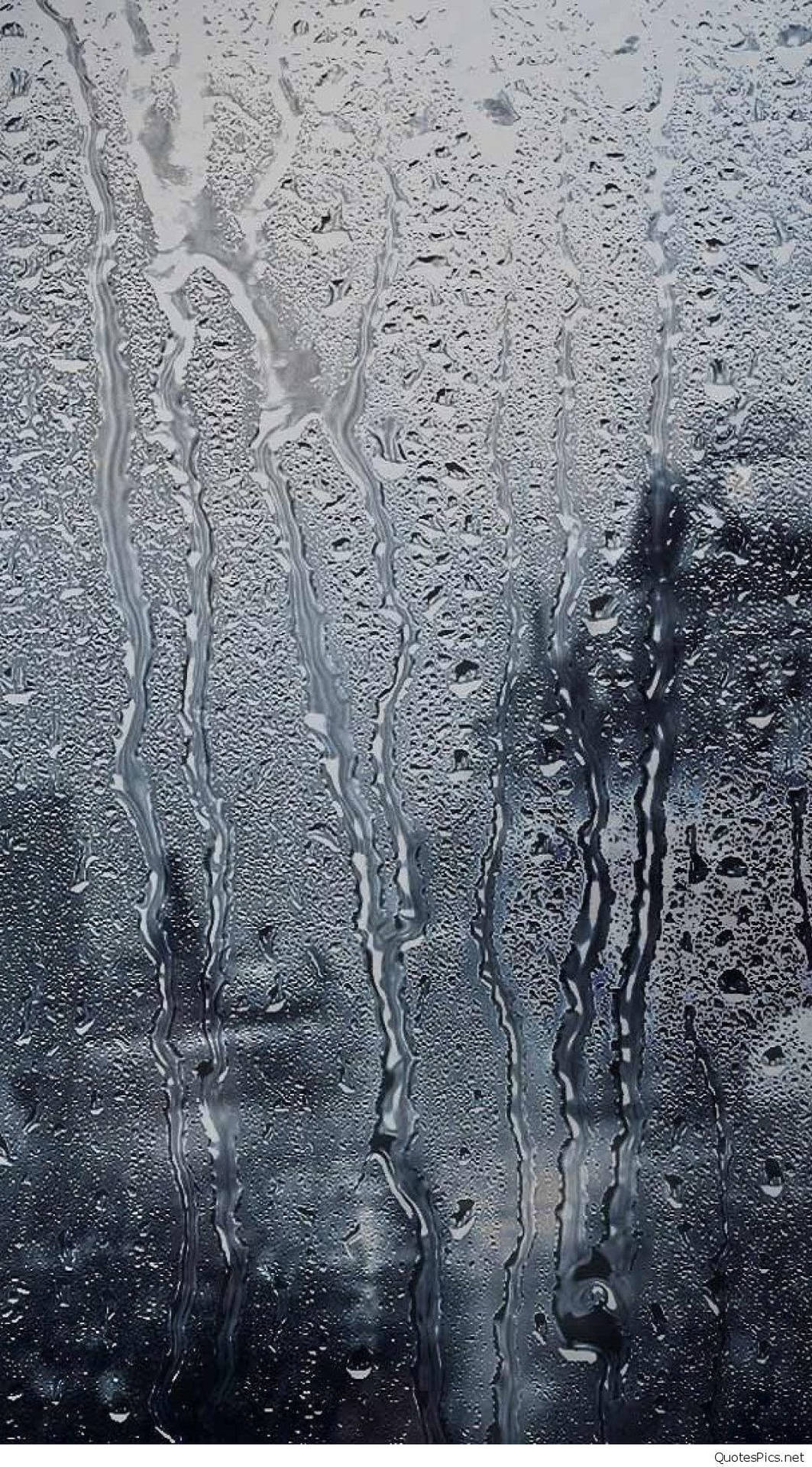 雨滴在玻璃窗上滑落，背景模糊。