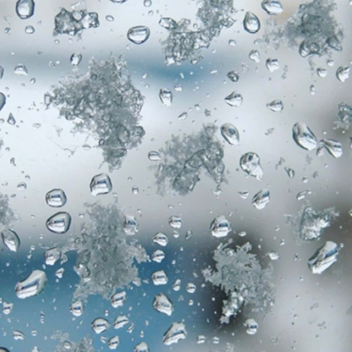 窗上的雨滴和霜，背景為模糊的天空。