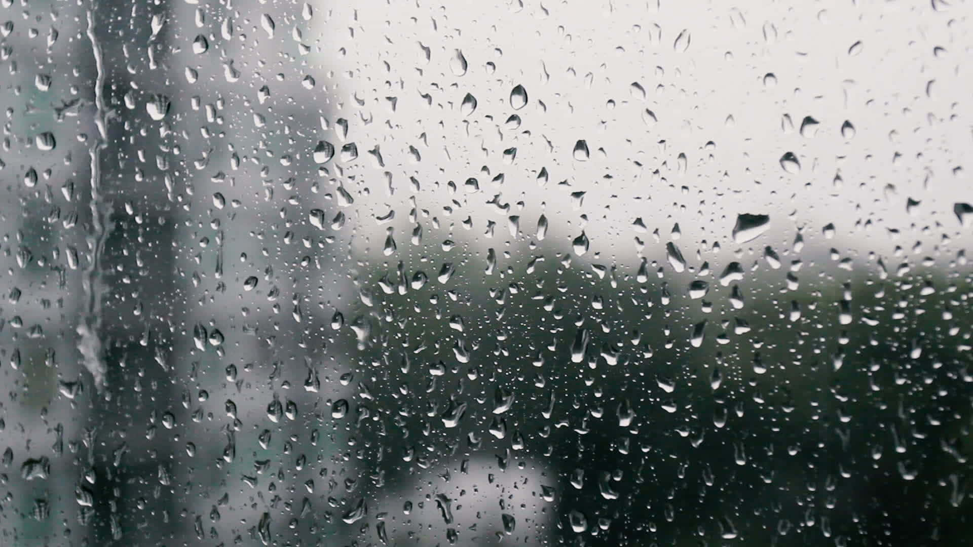 窗上的雨滴與模糊的城市背景