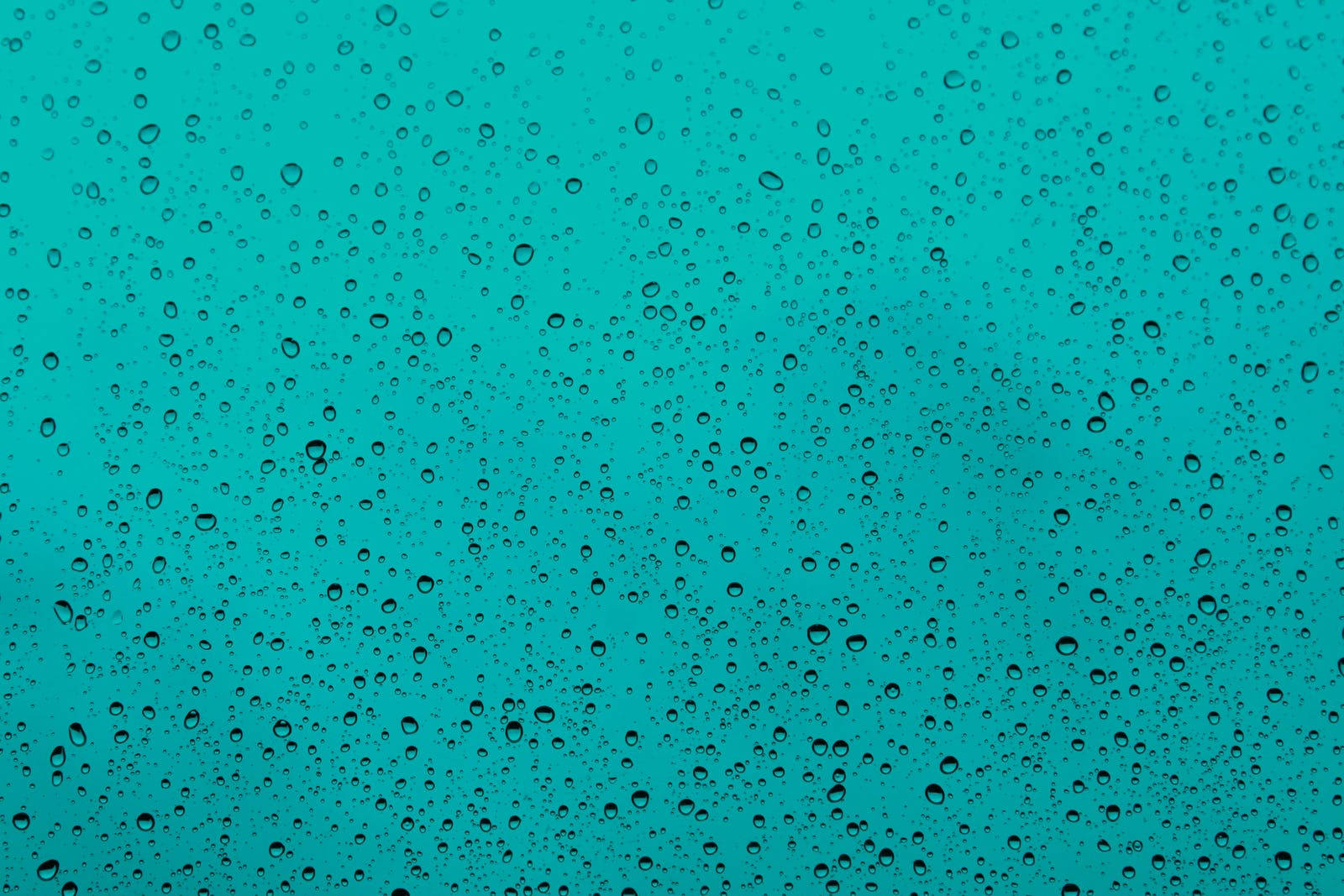 透過濺滿雨水的玻璃看到的青綠色天空