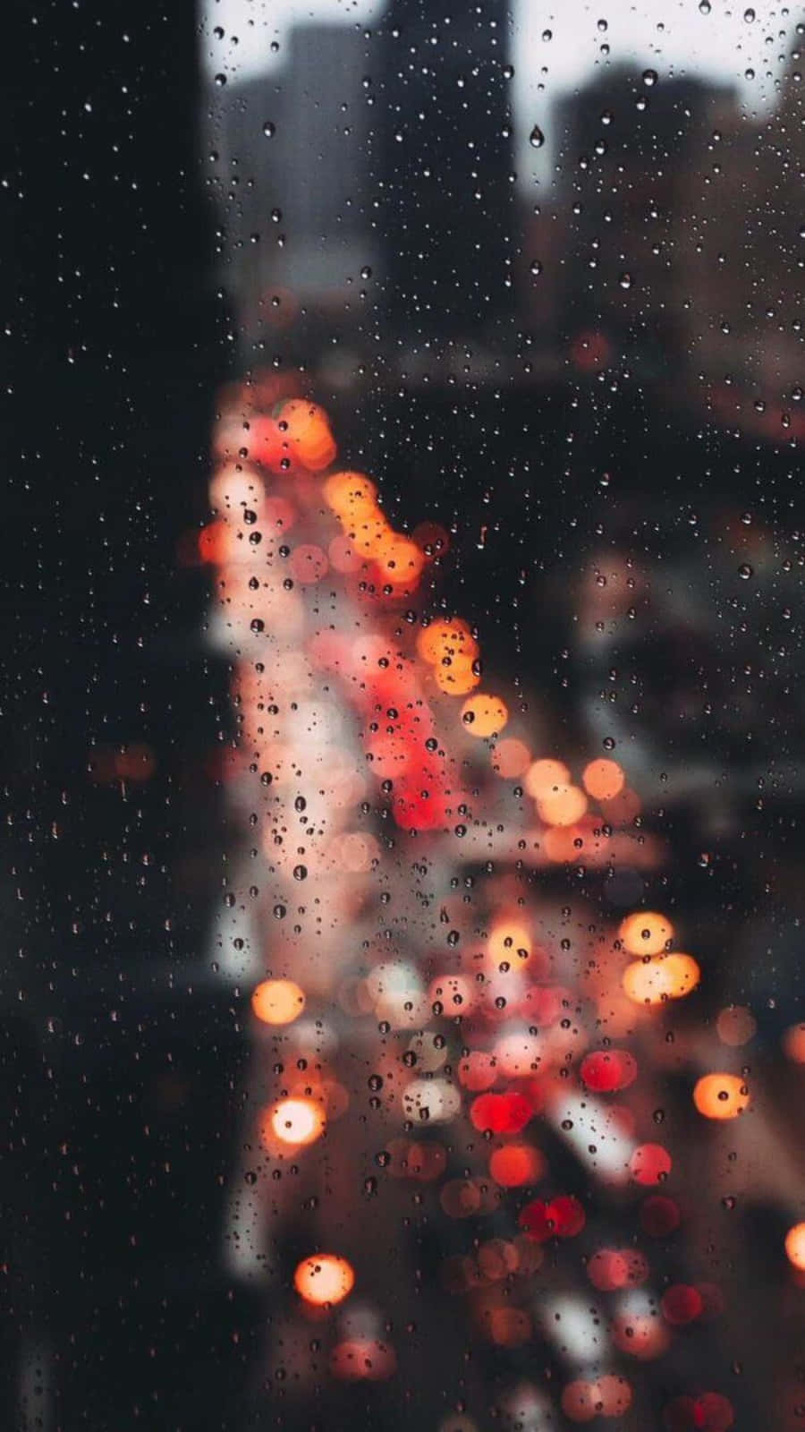 窗戶上的雨滴，夜晚模糊的城市燈光溫暖地發光。