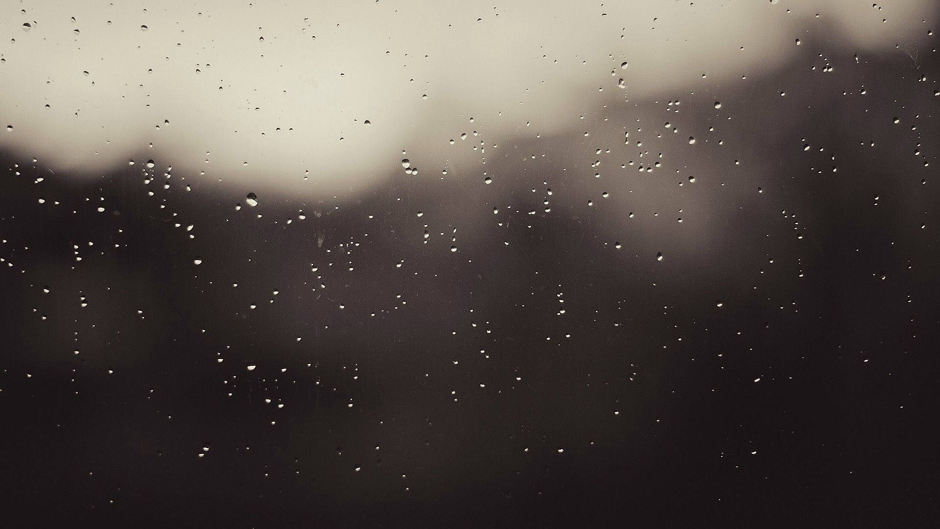 黑白 桌布 壁紙 — 雨滴依附在玻璃窗上，模糊的城市景觀逐漸消失在灰色的暮色中。