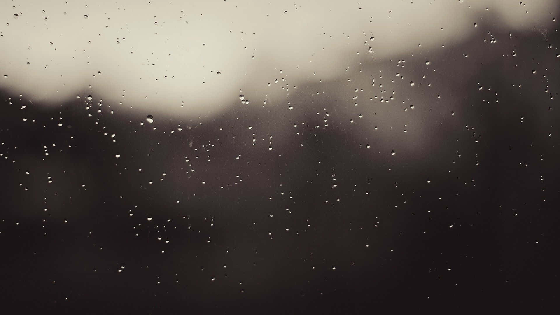 灰色美學 桌布 壁紙 — 雨滴依附在玻璃表面，將柔和的戶外場景模糊成柔和的灰色調。