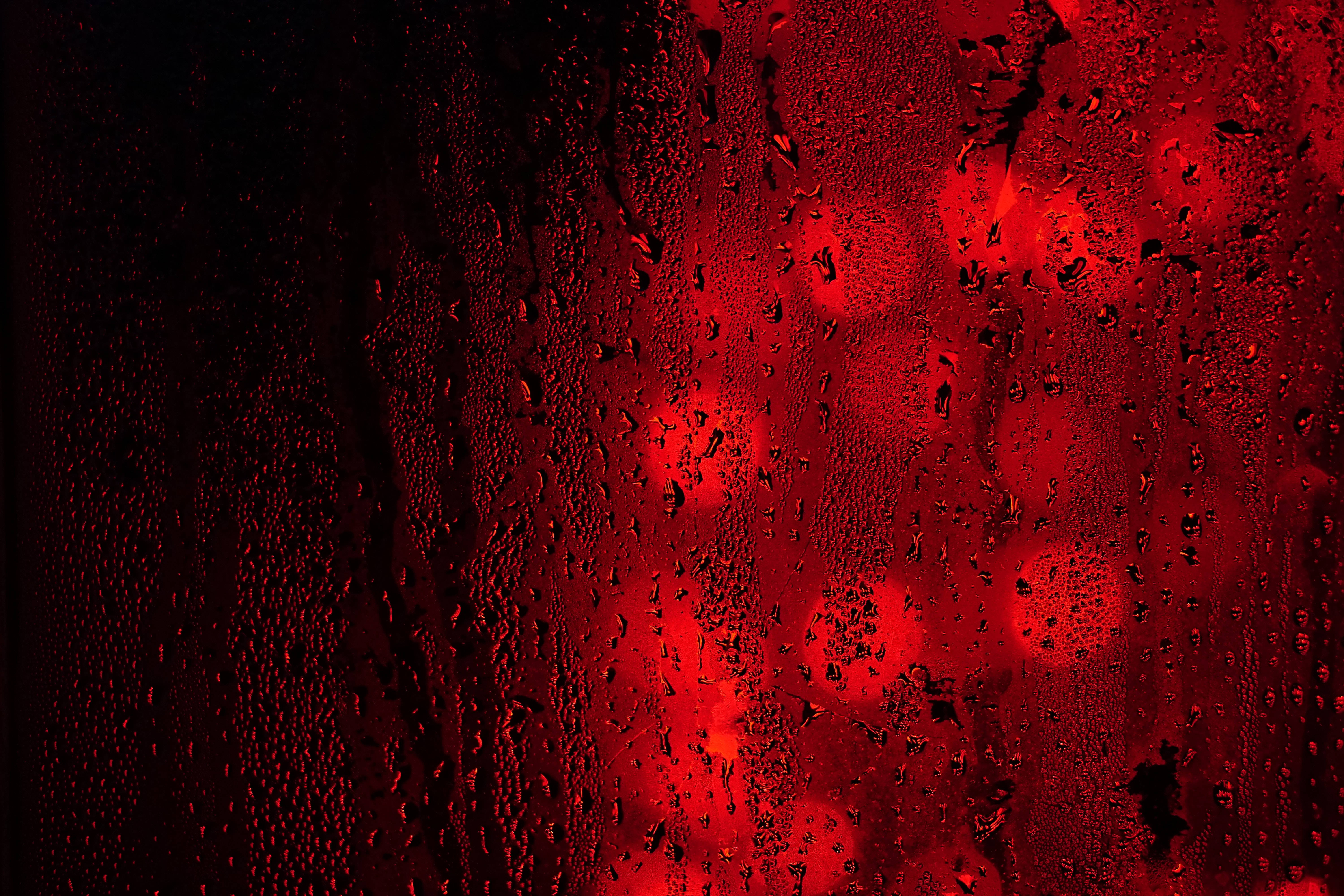 黑紅 桌布 壁紙 — 雨滴依附在窗戶上，顯露出黑暗夜晚中模糊的紅光。