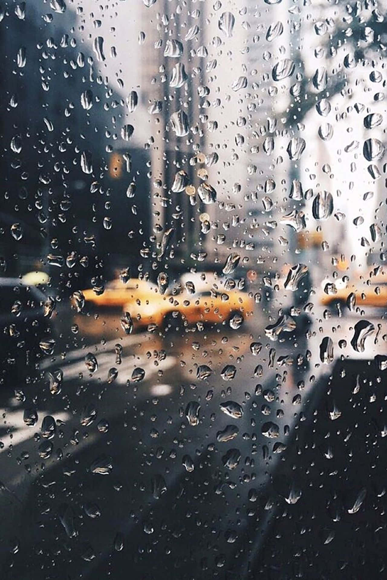 Rainy Day 桌布 壁紙 — 雨滴劃過窗戶，顯現出柔焦中模糊的黃色計程車和城市建築。