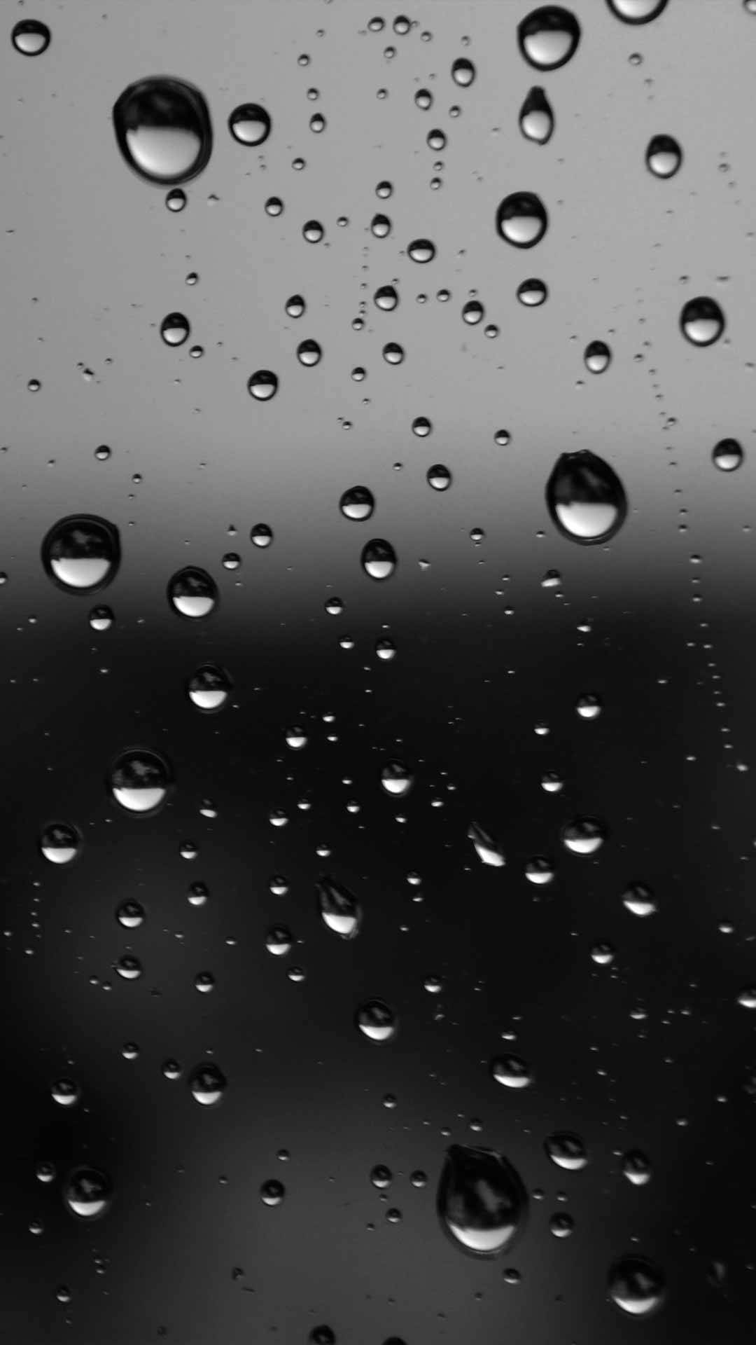 深色主題 桌布 壁紙 — 雨滴在深色玻璃表面上閃爍，營造出憂鬱的單色抽象圖案。