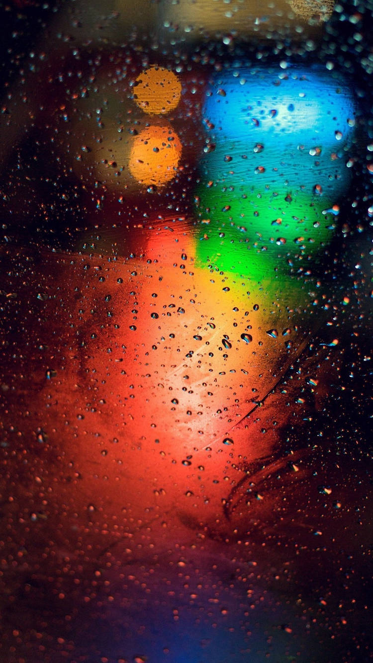 iPhone 桌布 壁紙 — 雨滴將夜間濕窗上充滿活力的城市燈光模糊成發光嘅散景。