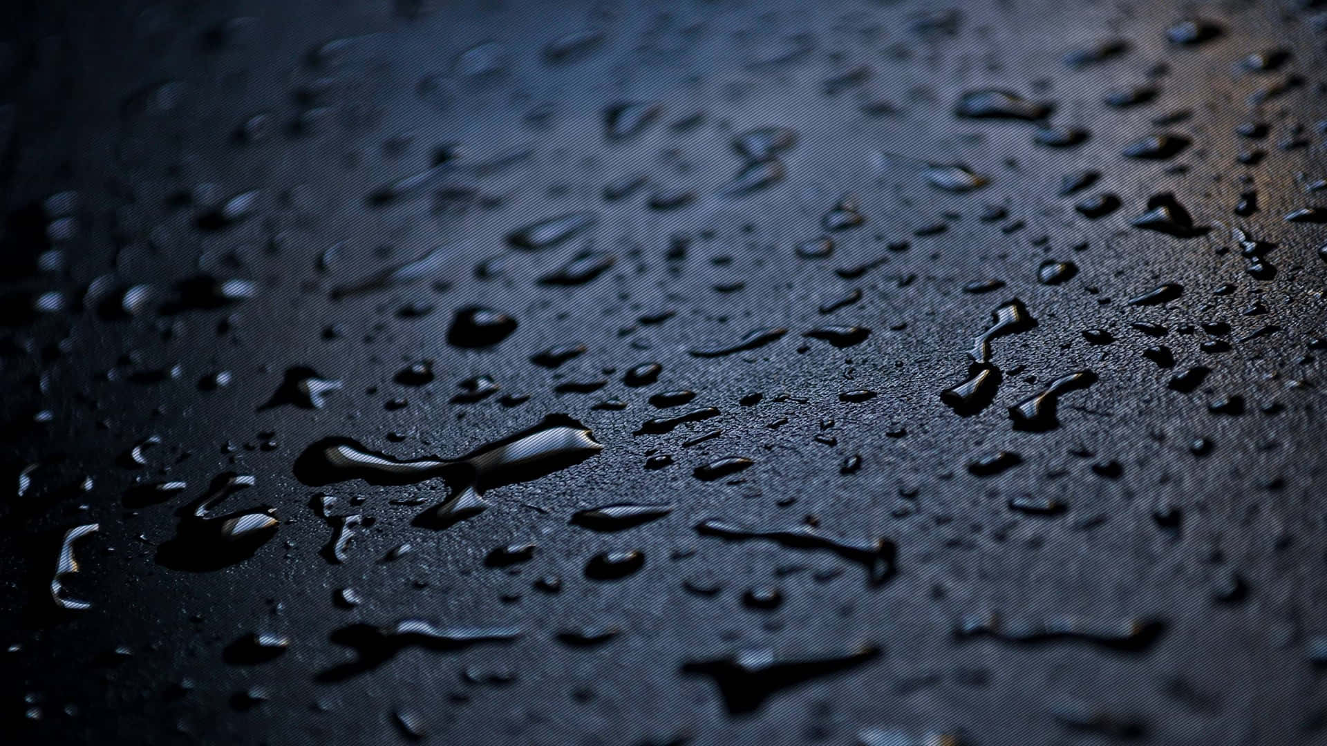 深色紋理表面上的雨滴特寫。