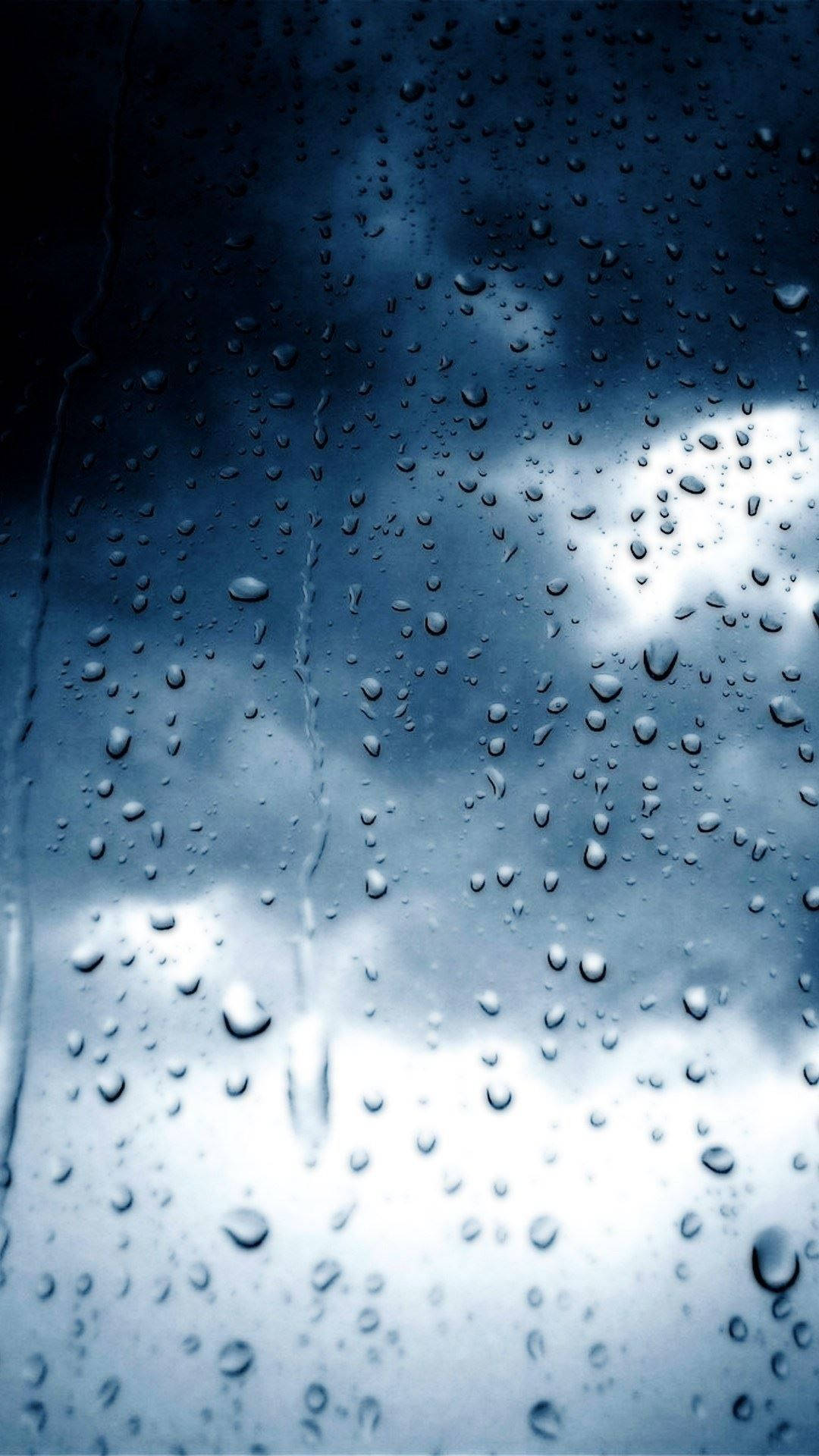 暴風 桌布 壁紙 — 雨滴沿玻璃窗流下，露出陰沉多雲的天空，帶有冷藍色調。