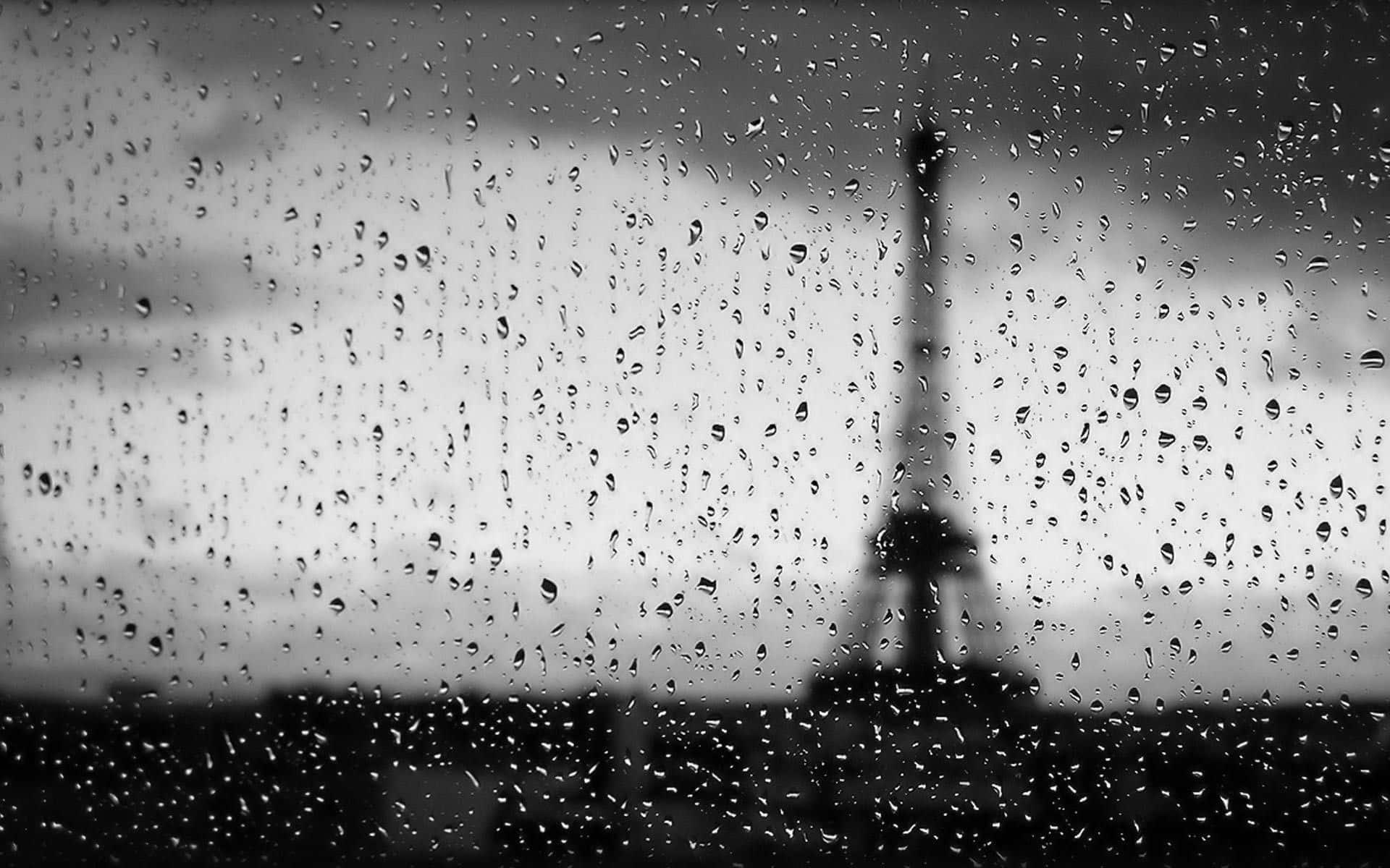Raining 桌布 壁紙 — 雨滴沿窗戶流下，顯現出灰色天空背景下模糊的艾菲爾鐵塔輪廓。