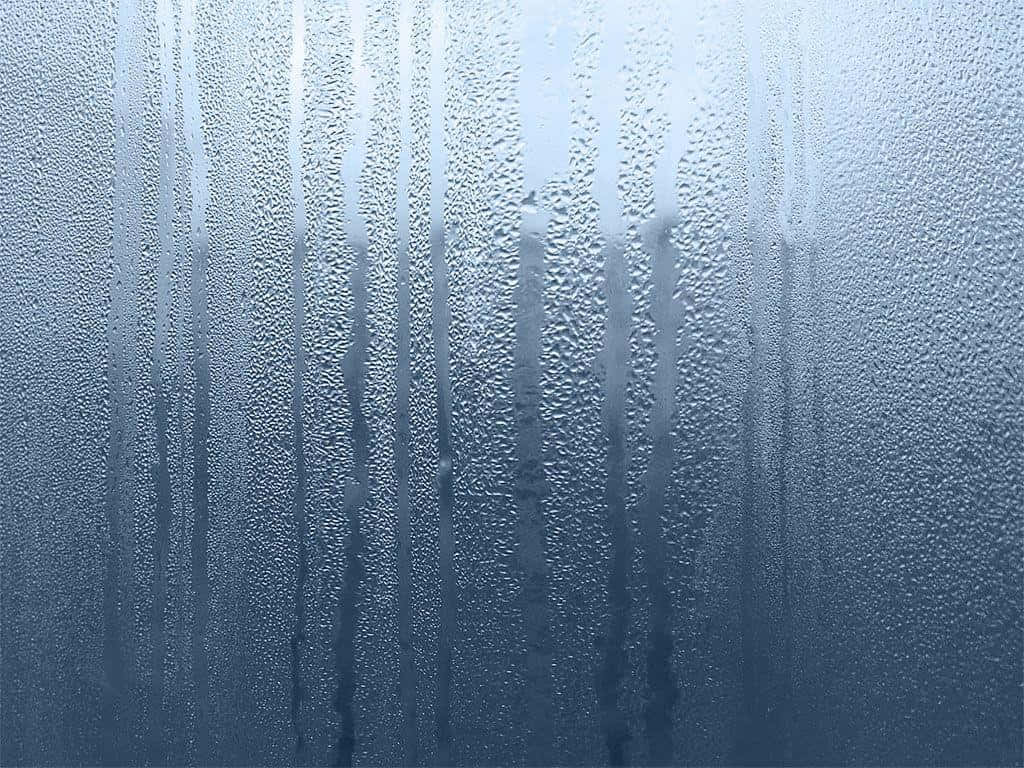 帶有藍色調的窗戶，有雨滴和冷凝條紋。