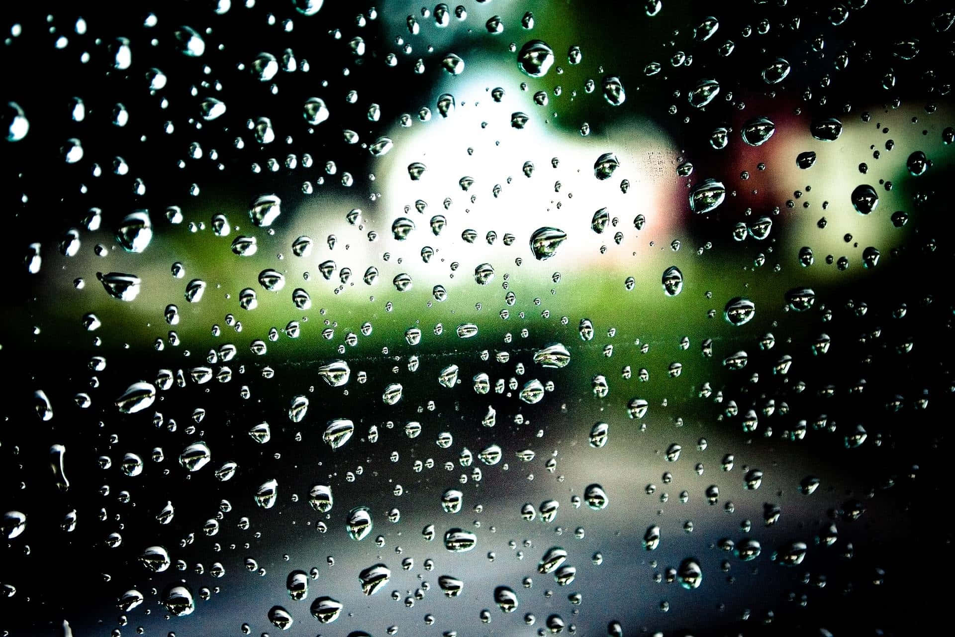窗戶上的雨滴，背景模糊的綠色和白色。