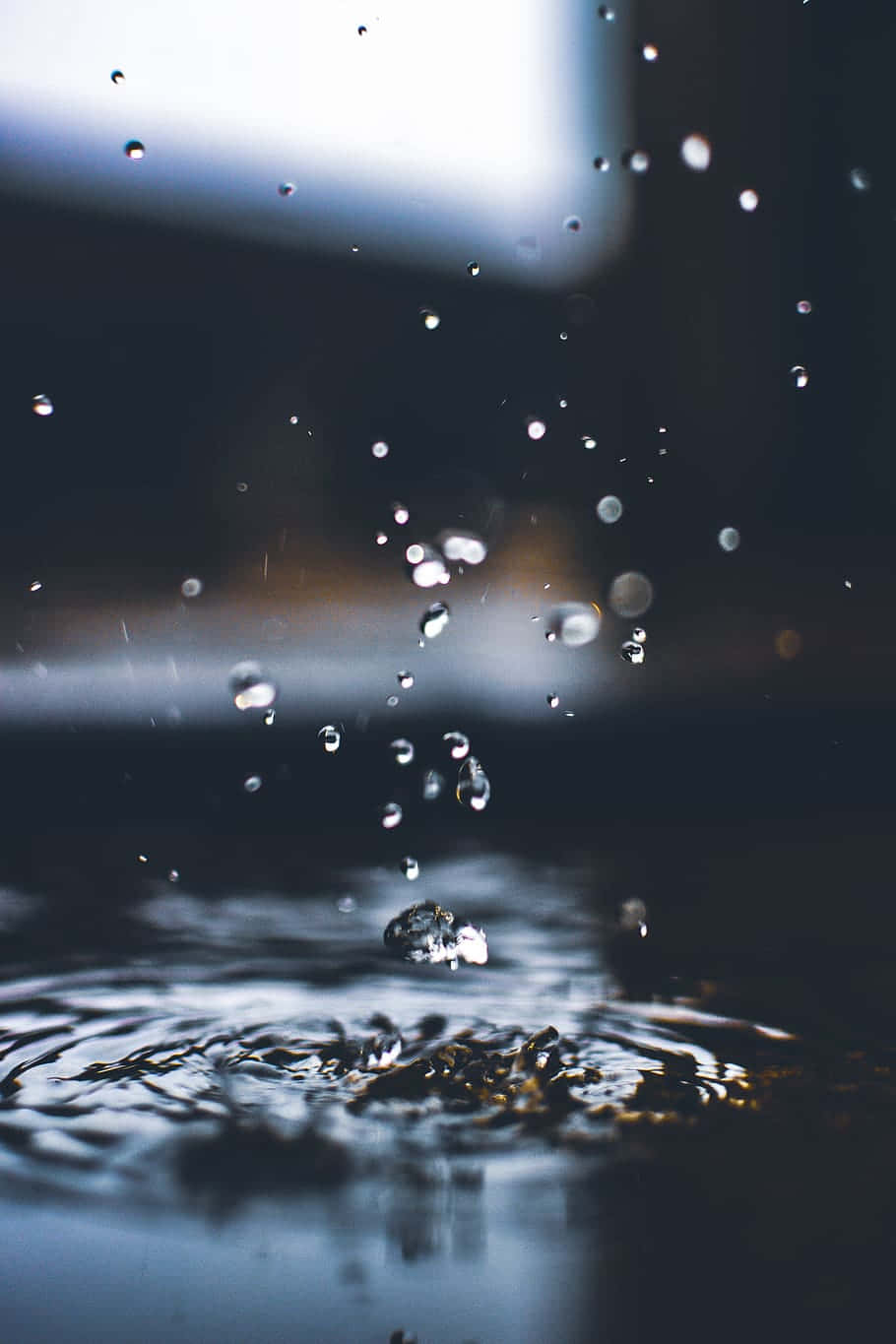 雨點濺入水中產生漣漪和飛濺的水滴。