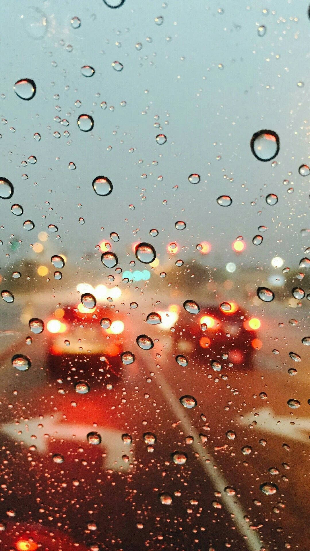 夜間汽車窗戶上的雨滴與模糊的城市燈光。