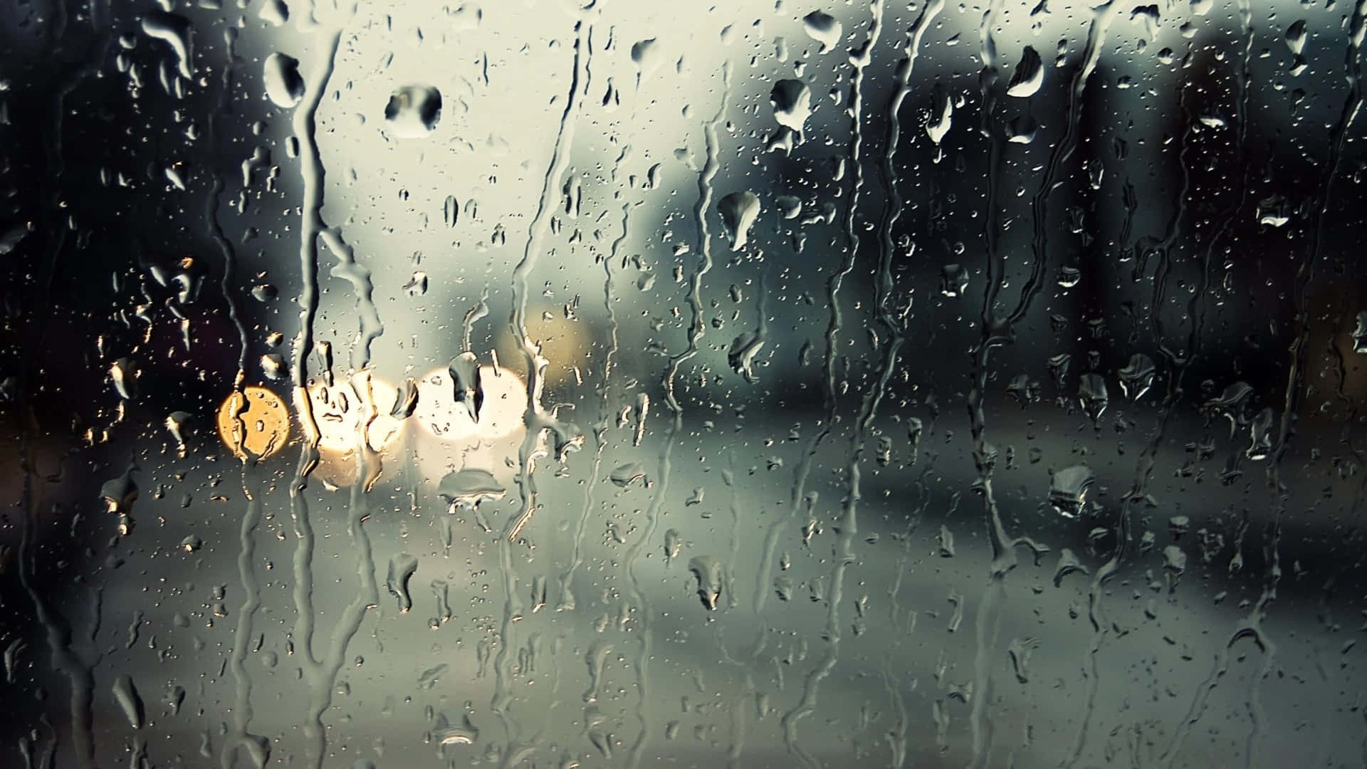 車窗上的雨滴，背景中模糊的街燈發光。