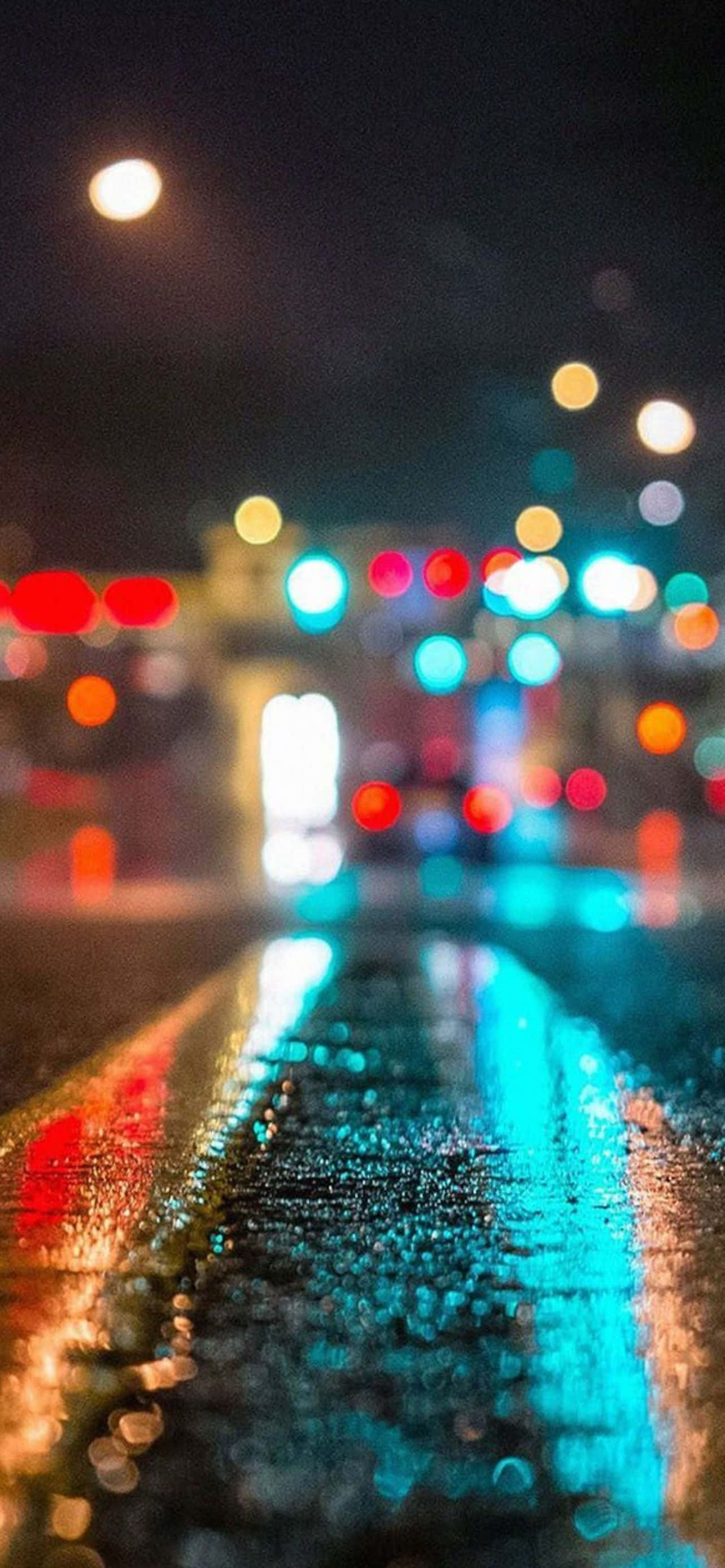 型格 iPhone 壁紙 桌布 壁紙 — 雨濕的夜間城市街道反射來自交通和街燈的發光散景燈光。