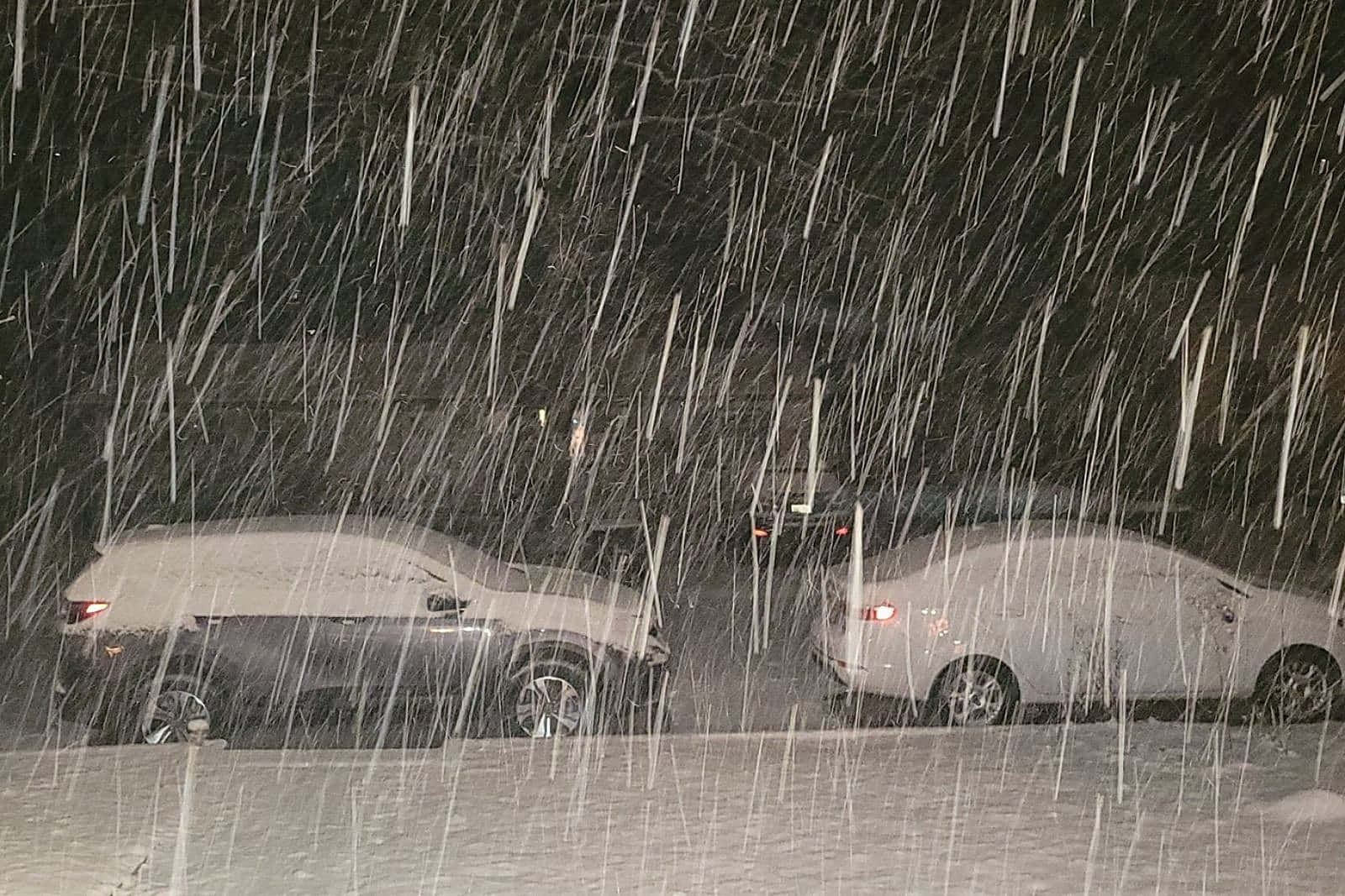 夜間暴風雪中，兩輛停在外面的積雪汽車。