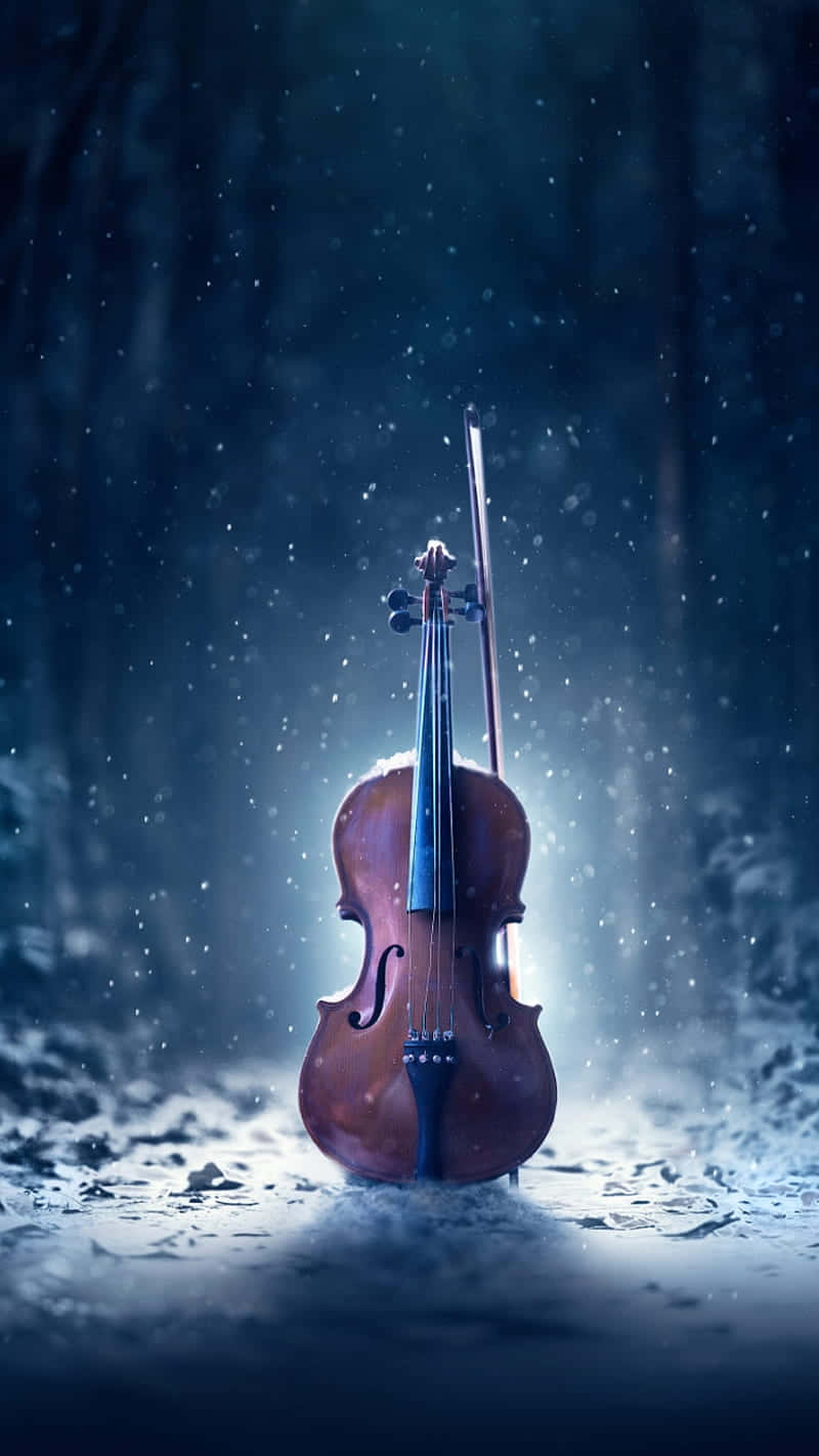 小提琴和琴弓在夜間藍色森林下的雪中站立。