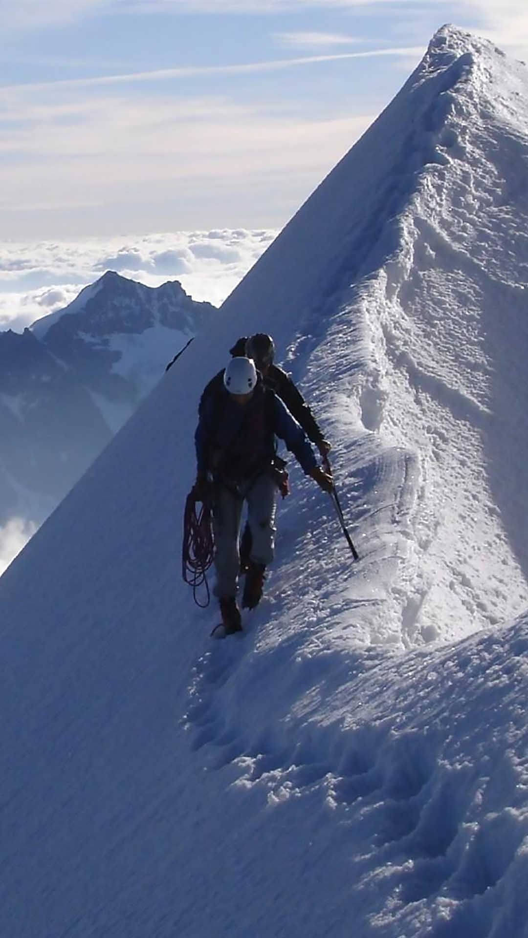 兩名登山者在雲上攀登積雪山脊