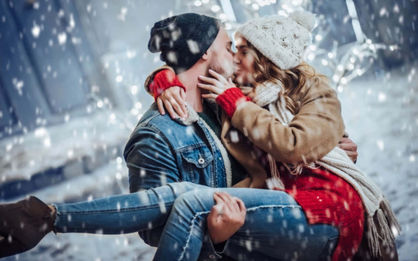 雪中情侶親吻畫面 壁紙 — 一對情侶在飄雪中熱情接吻，戴著冬季帽子、圍巾和外套。