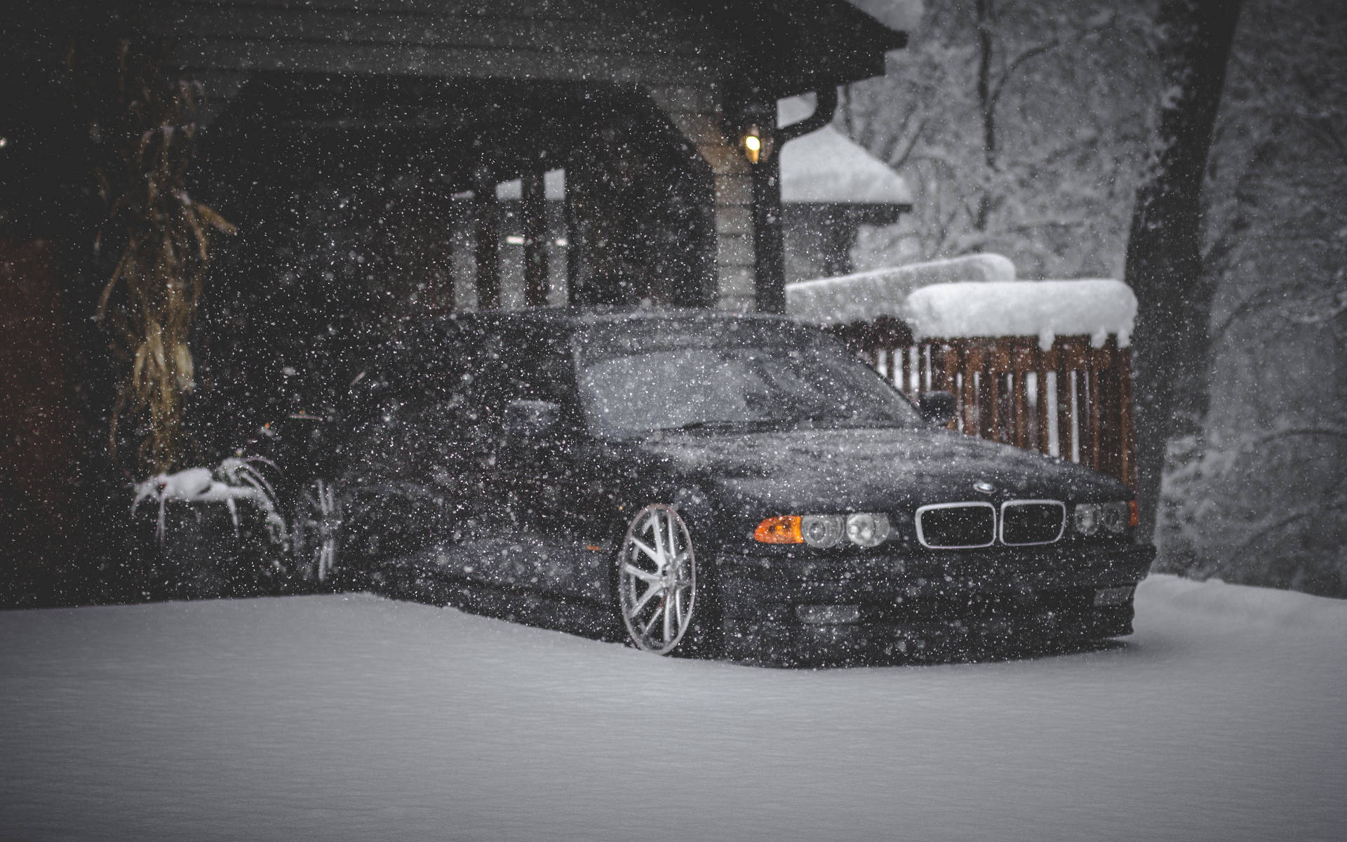 黑色BMW轎車在冬夜停在雪中，雪花飄落。