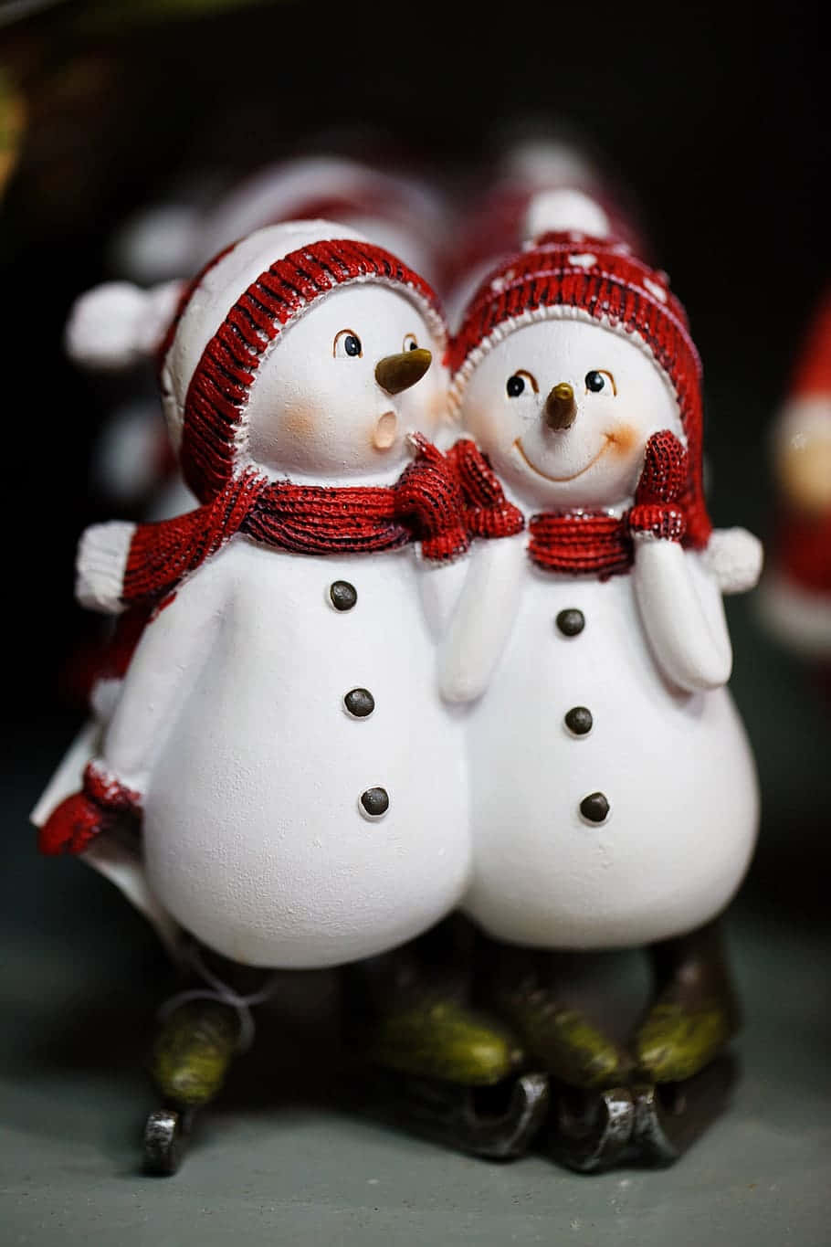 兩個戴著紅色帽子和圍巾的雪人公仔穿著溜冰鞋。