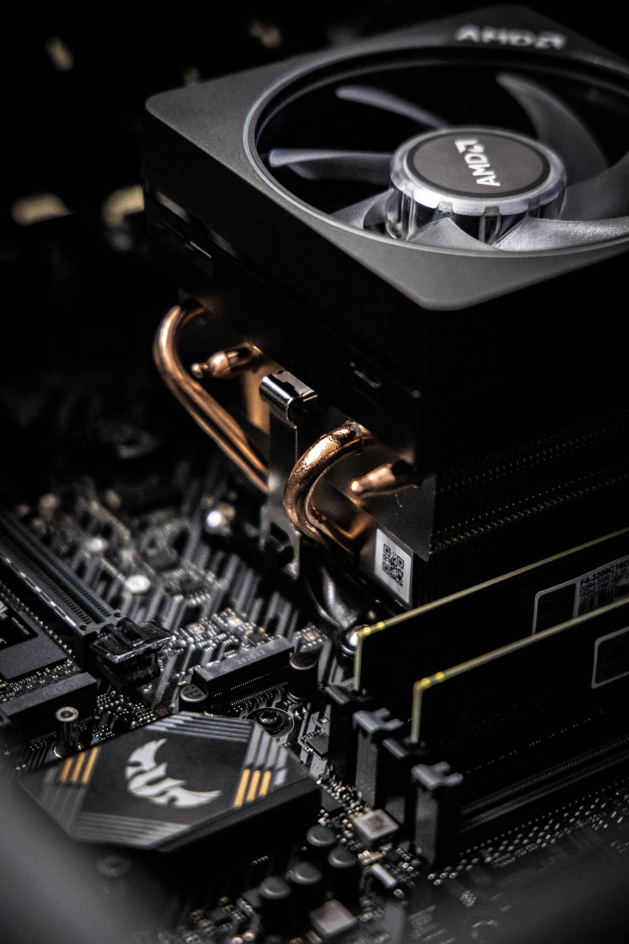 AMD CPU 散熱器和主機板特寫，帶有銅管和發光標誌。