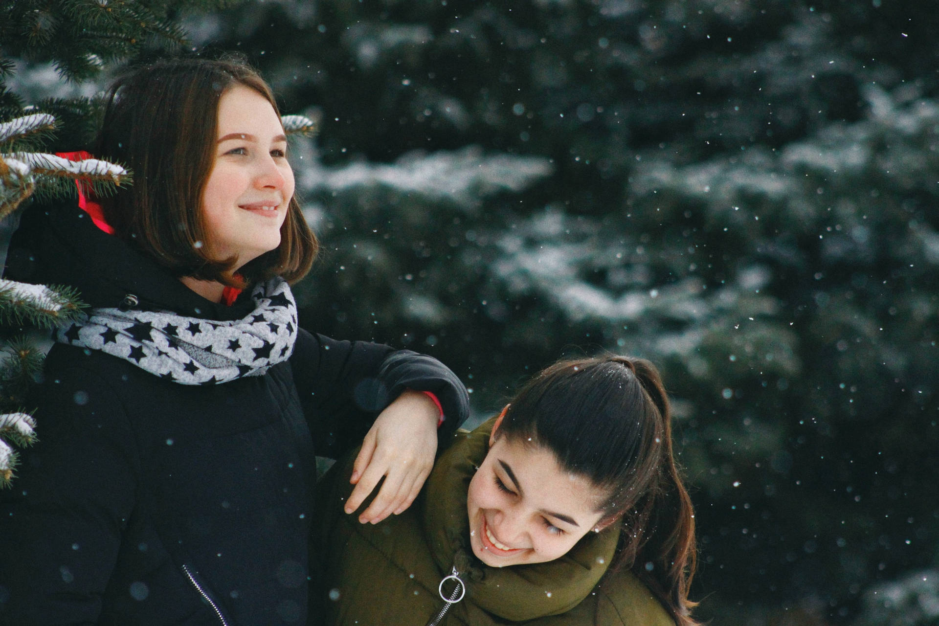 兩位女性在雪地森林中微笑擁抱。