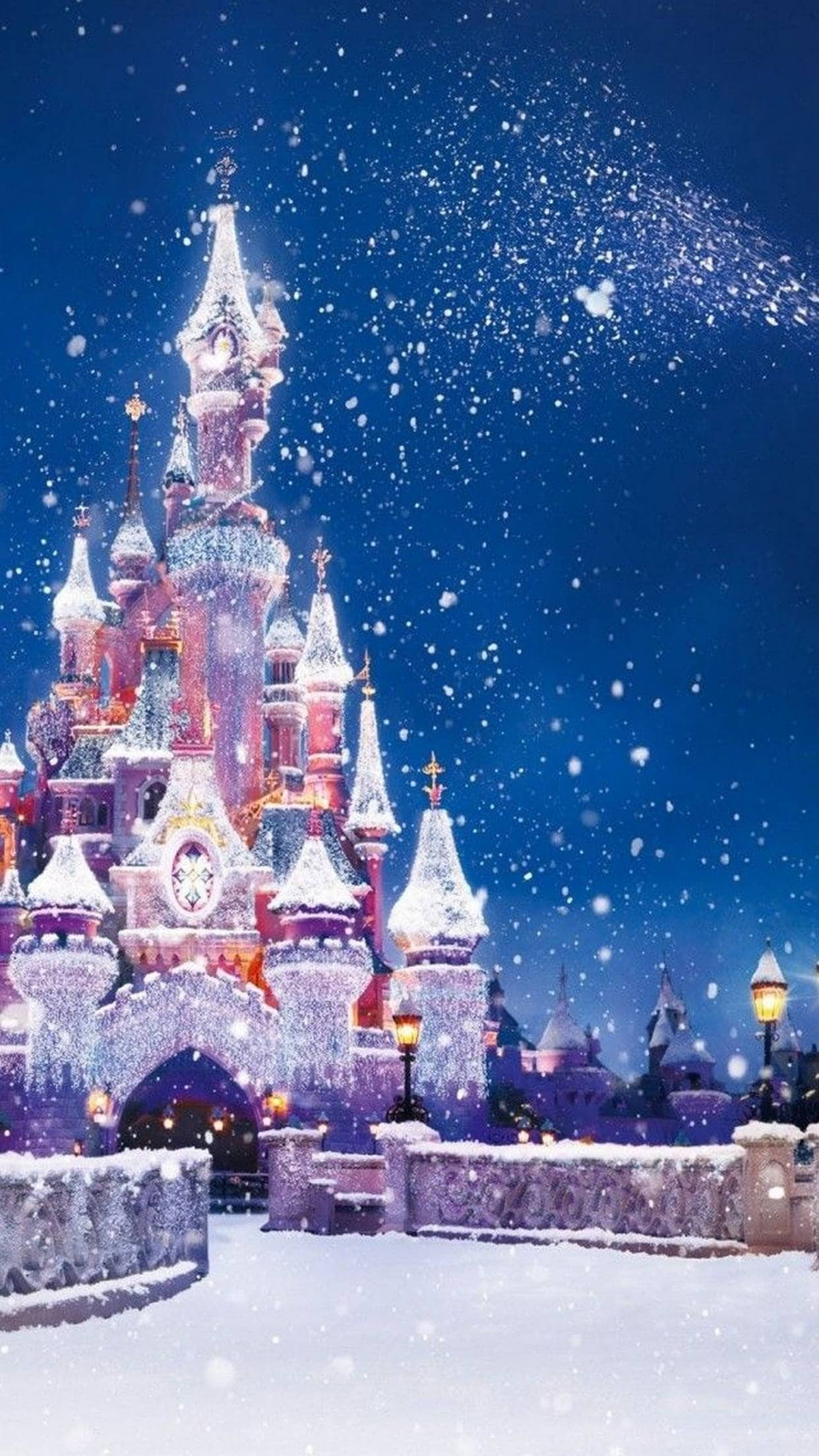 雪堡聖誕 iPhone 壁紙 — 一座雄偉的雪城堡在繁星點點的夜空下溫暖地發光，雪花輕輕飄落。
