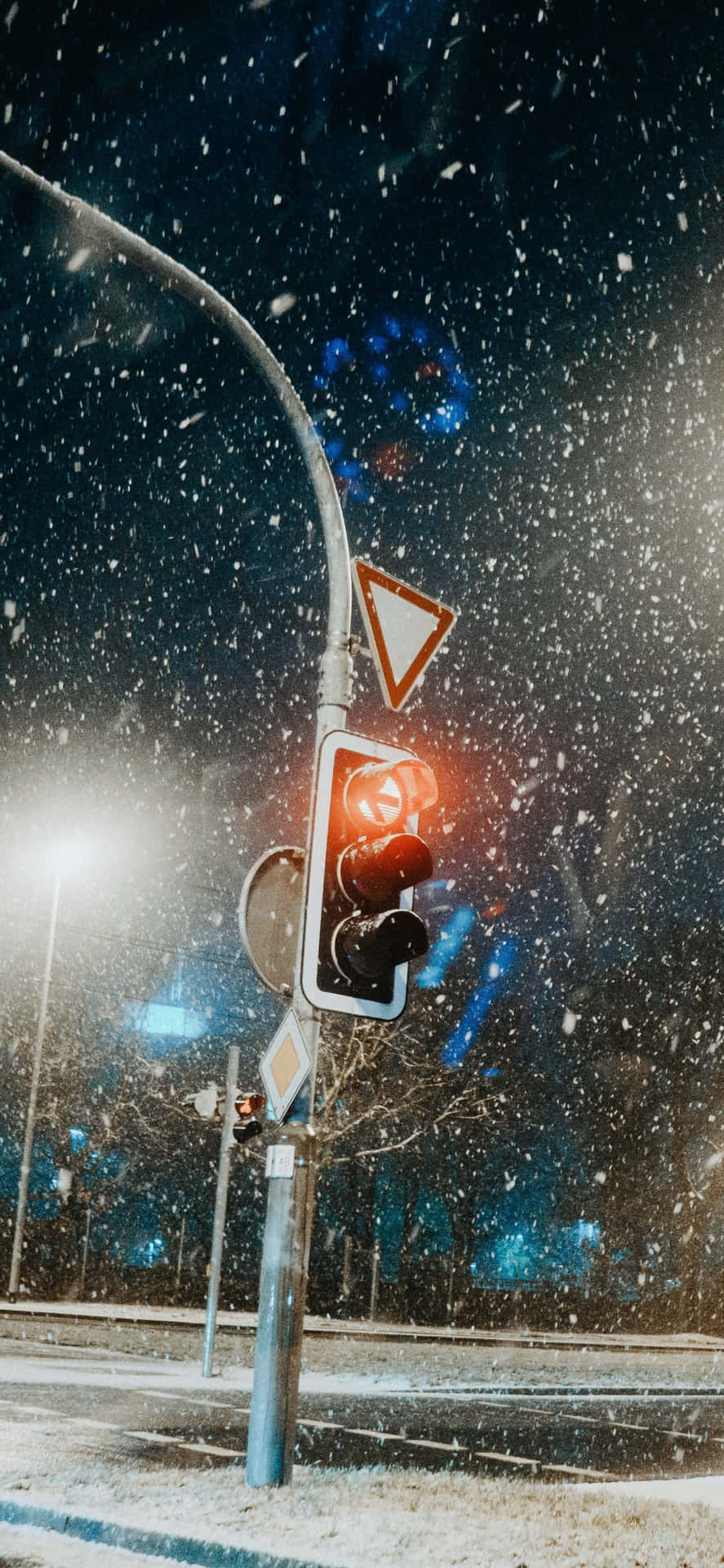紅色交通燈在夜間城市街道的飄雪中發光。