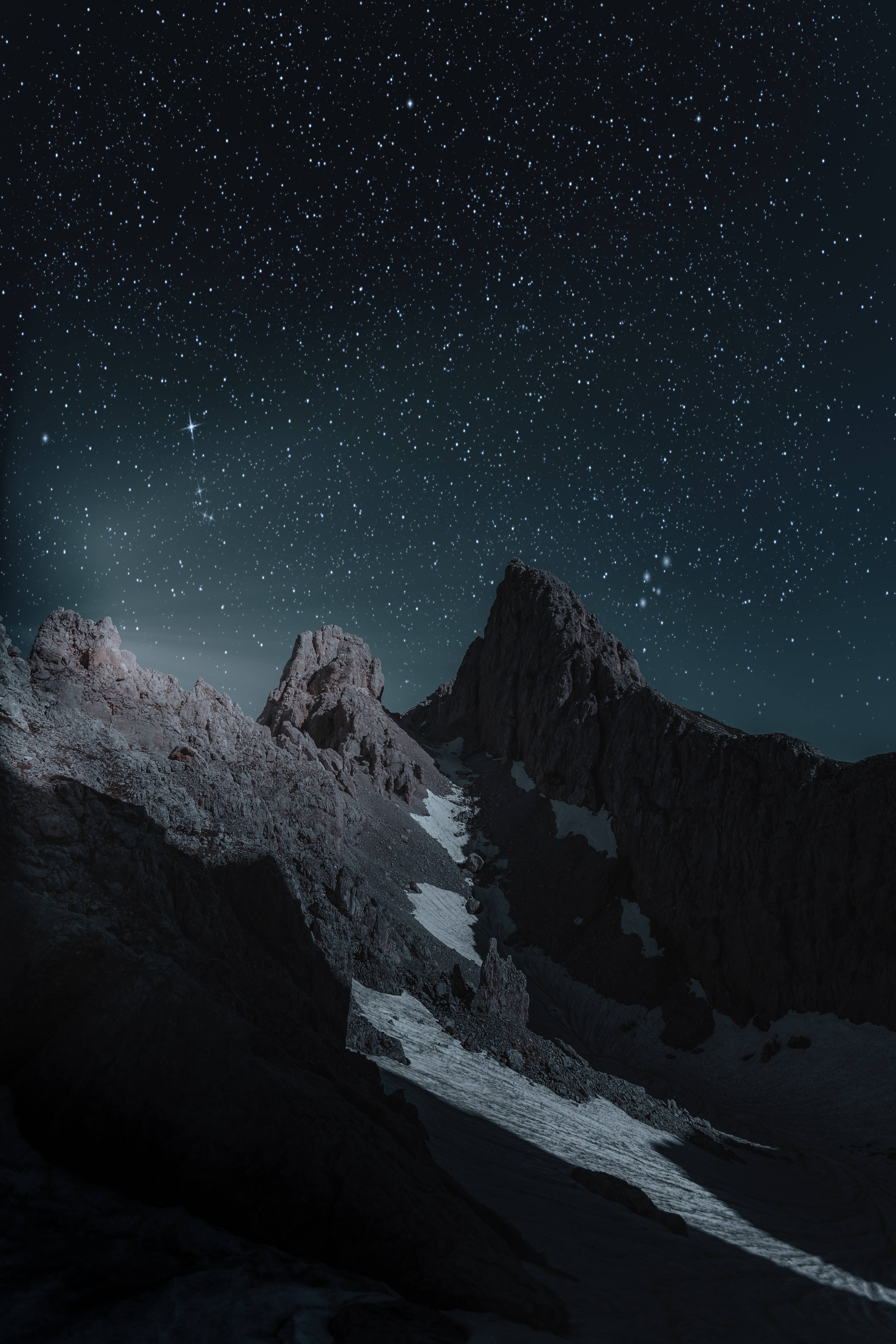 雪夜山景 iPhone 解鎖畫面 壁紙 — 在深邃的靛藍色夜空下，繁星點點的夜空覆蓋著鋸齒狀的積雪山峰。