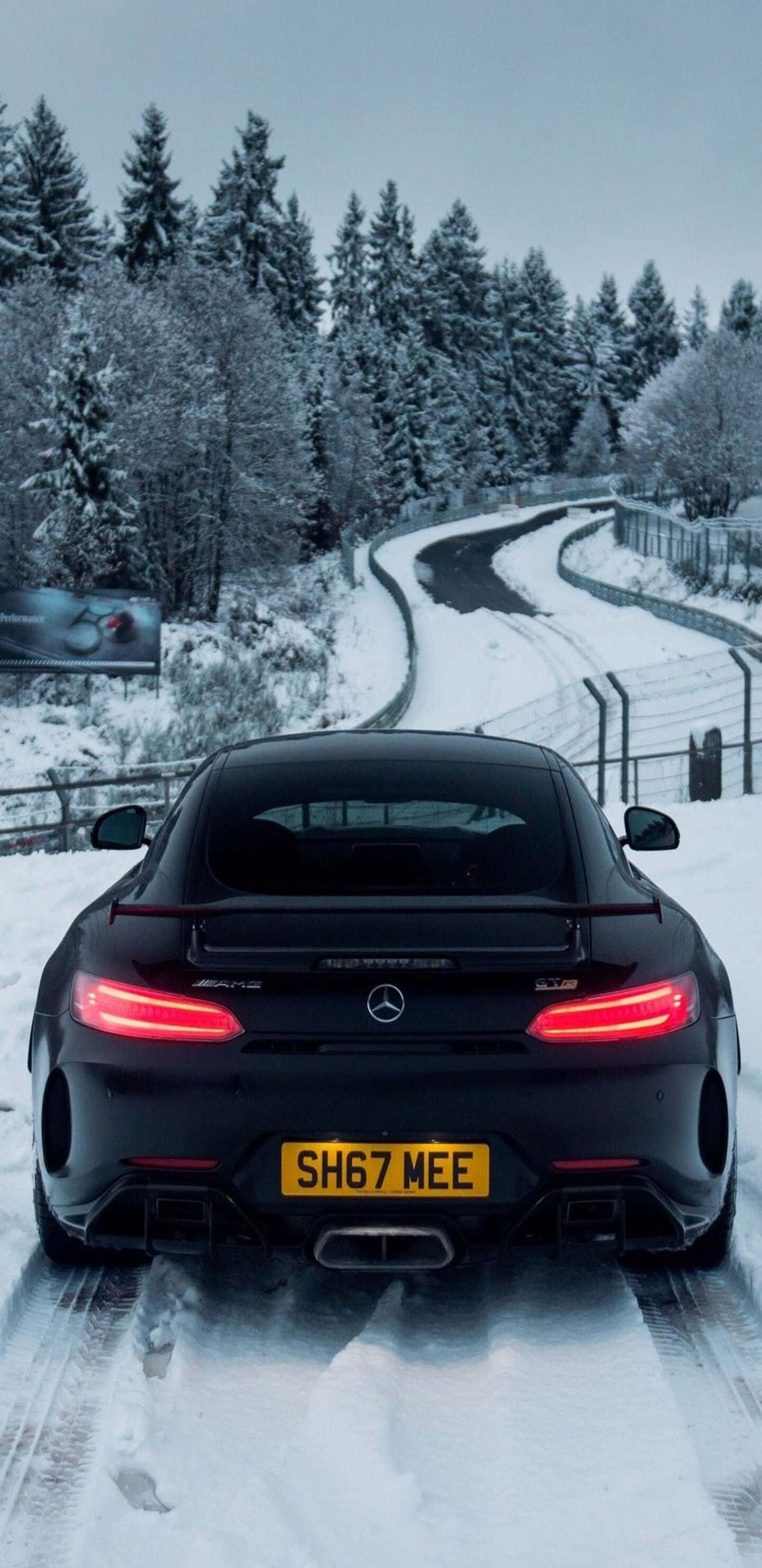 雪天中的梅賽德斯-奔馳 Pixel 3XL AMG GT-R背景 壁紙 — 一輛黑色Mercedes-AMG GT R在雪地森林道路上行駛，紅色尾燈在冬季樹木間閃爍。
