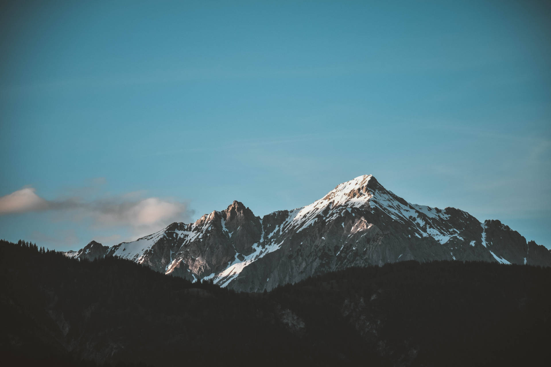 晴朗藍天下白雪覆蓋的山峰，雲朵飄浮。