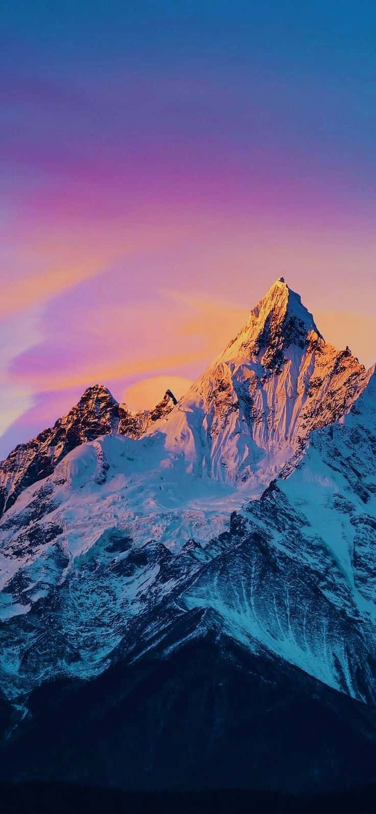 在紫色天空下，被金色夕陽沐浴的雪山峰。