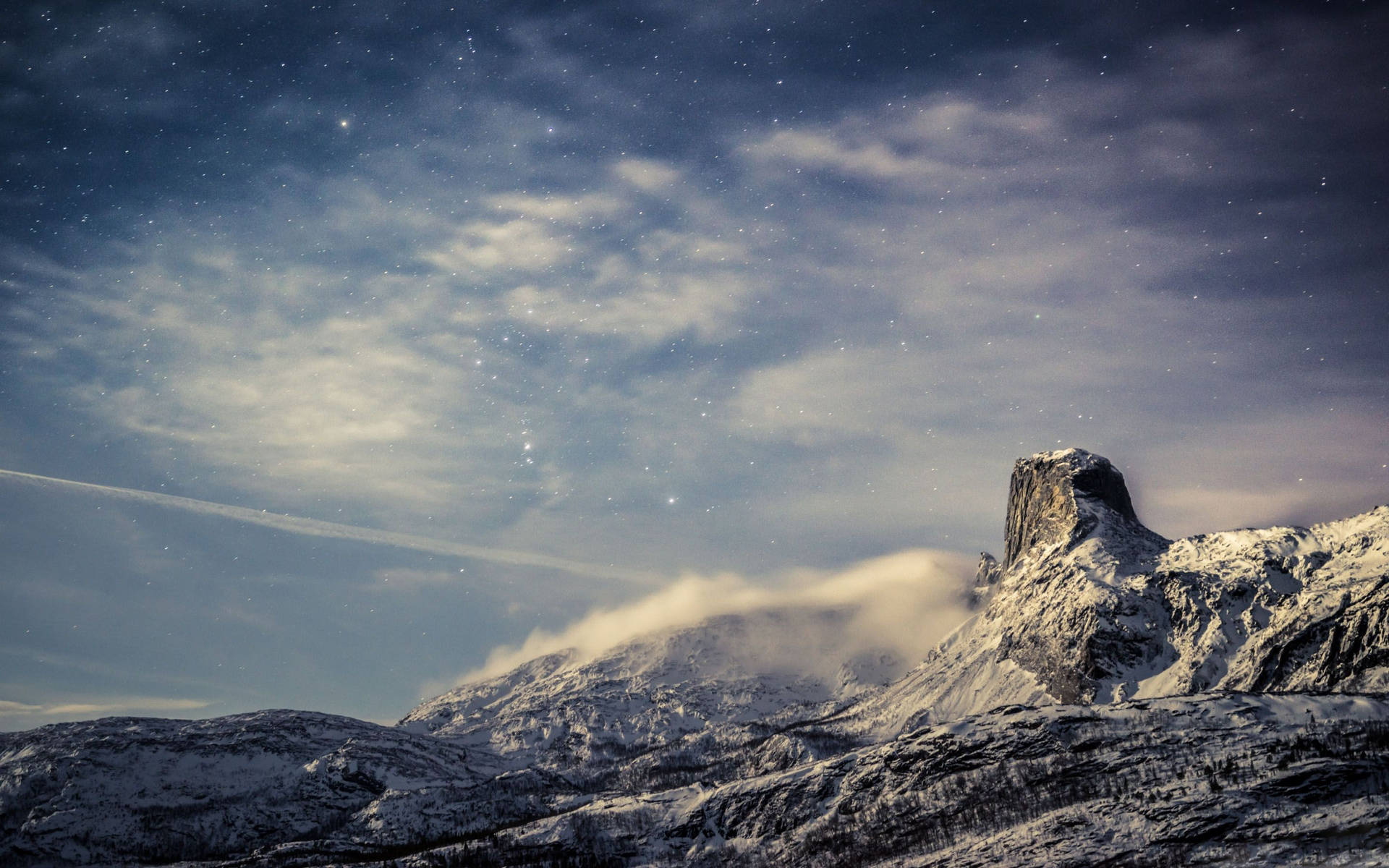 積雪的山峰在星光燦爛的暮色天空下，雲彩飄過。