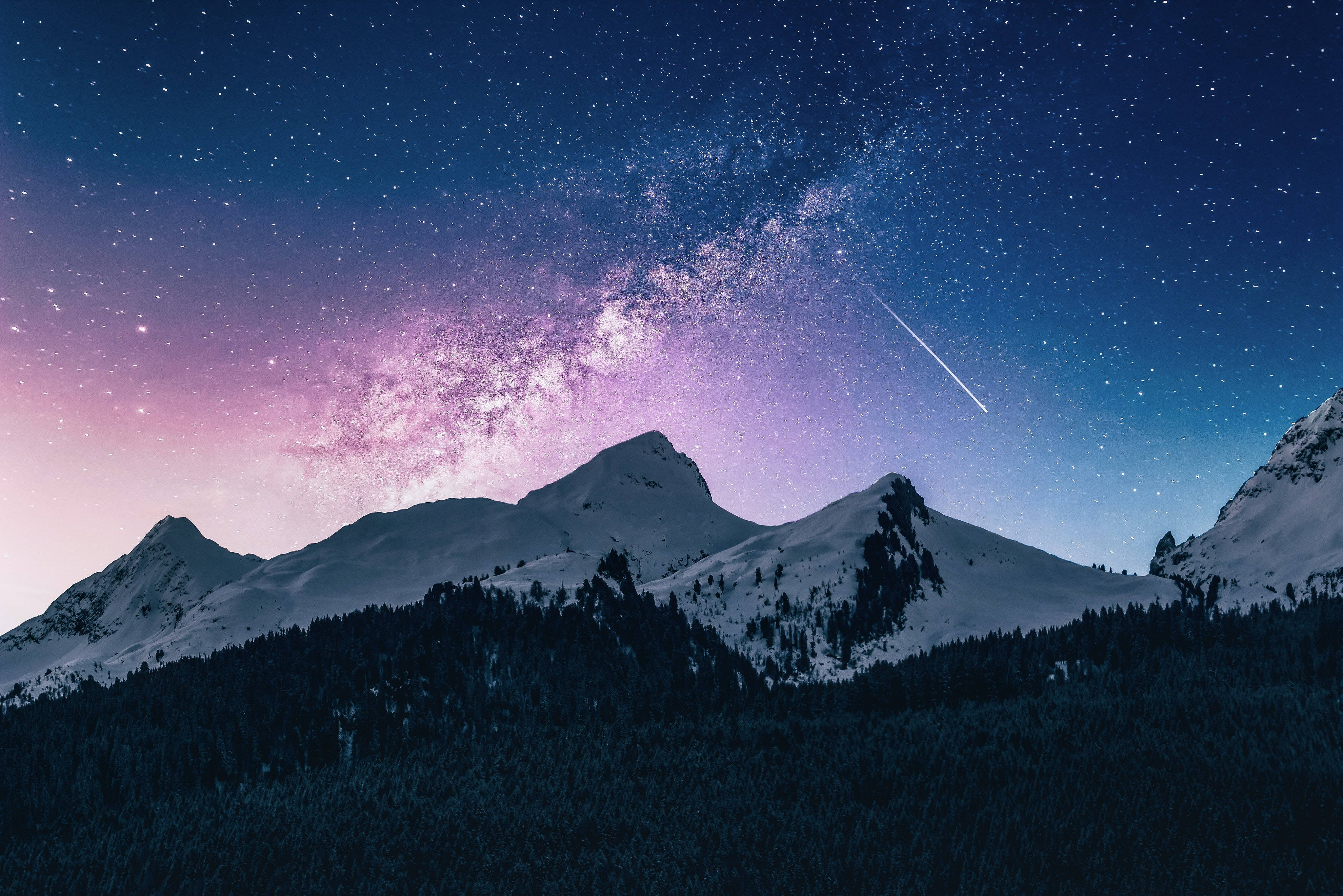 雪山與繁星夜空高清風景桌面 壁紙 — 積雪的山峰在充滿活力的星空下升起，伴隨著發光的銀河和流星。