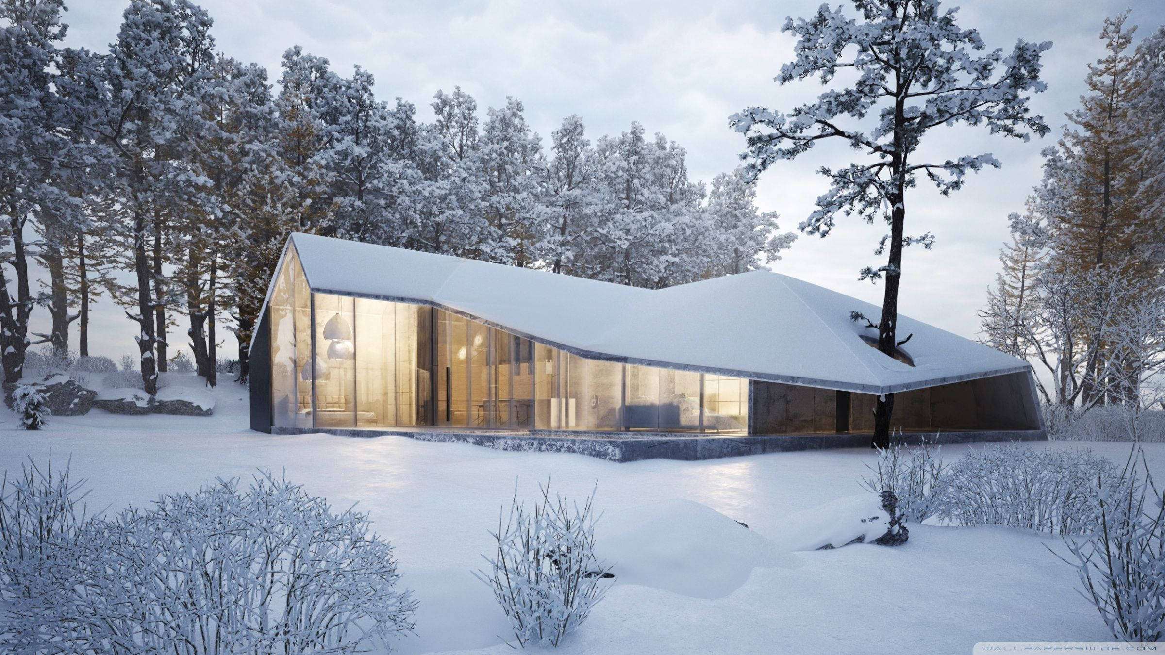 雪景中的現代住宅 壁紙 — 一座現代玻璃屋，屋頂覆蓋著雪，在暮色中的雪林裡溫暖地發光。